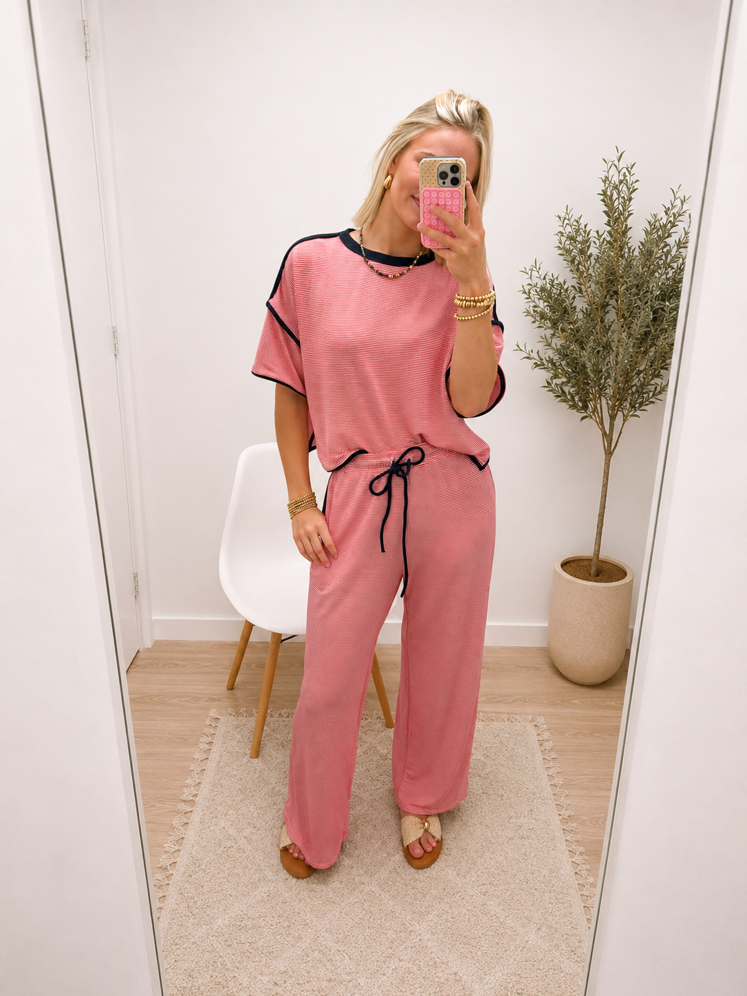Woman wearing a red striped matching set with black trim, short-sleeve top and wide-leg drawstring pants.