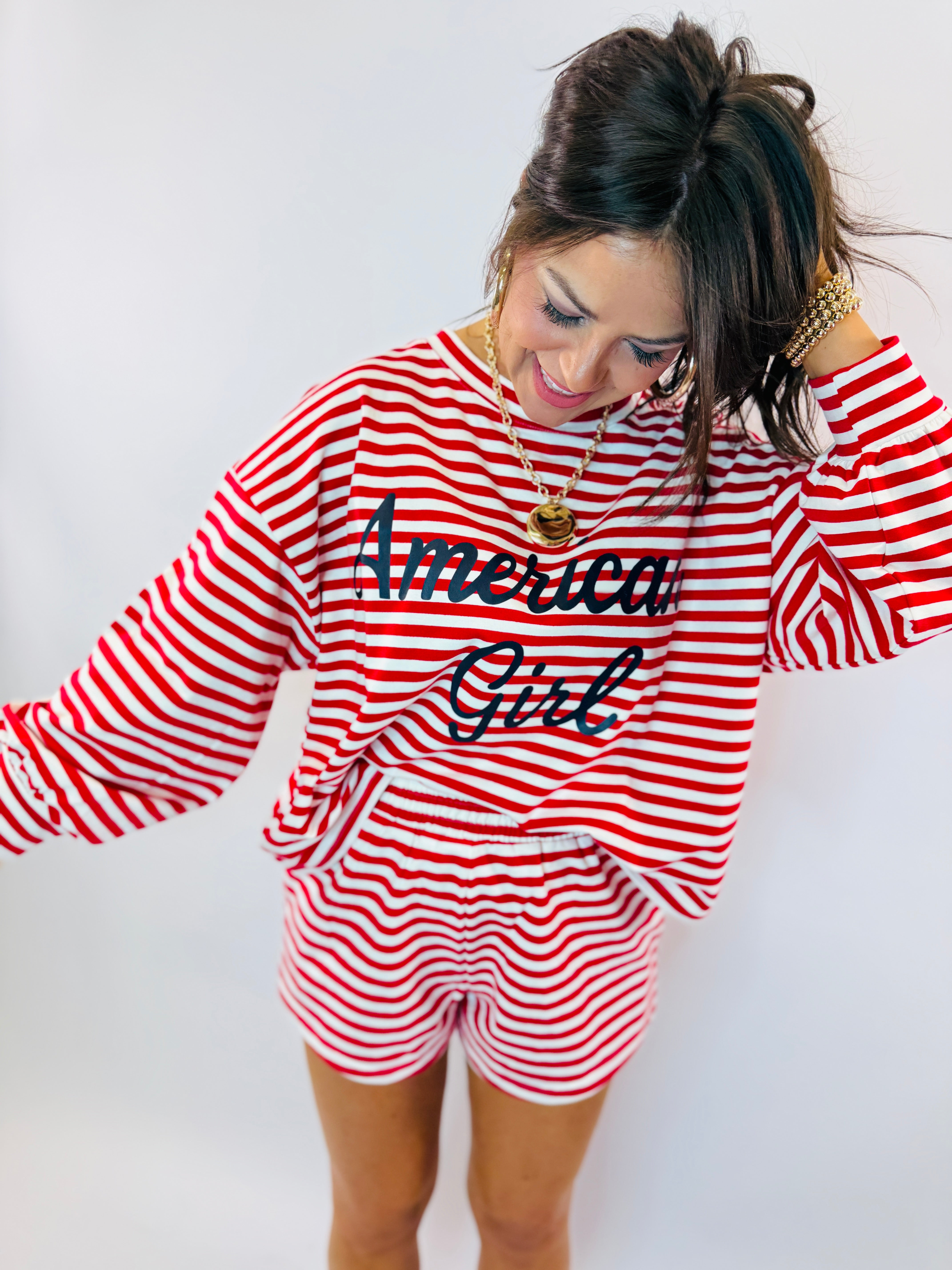 Woman wearing red and white striped long-sleeve top with "American Girl" text and matching striped shorts.
