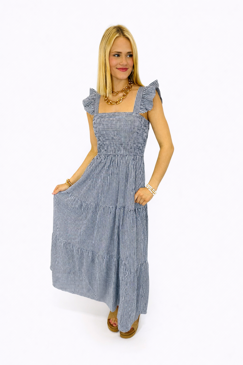 Woman wearing blue and white gingham midi dress with ruffle sleeves and tiered skirt