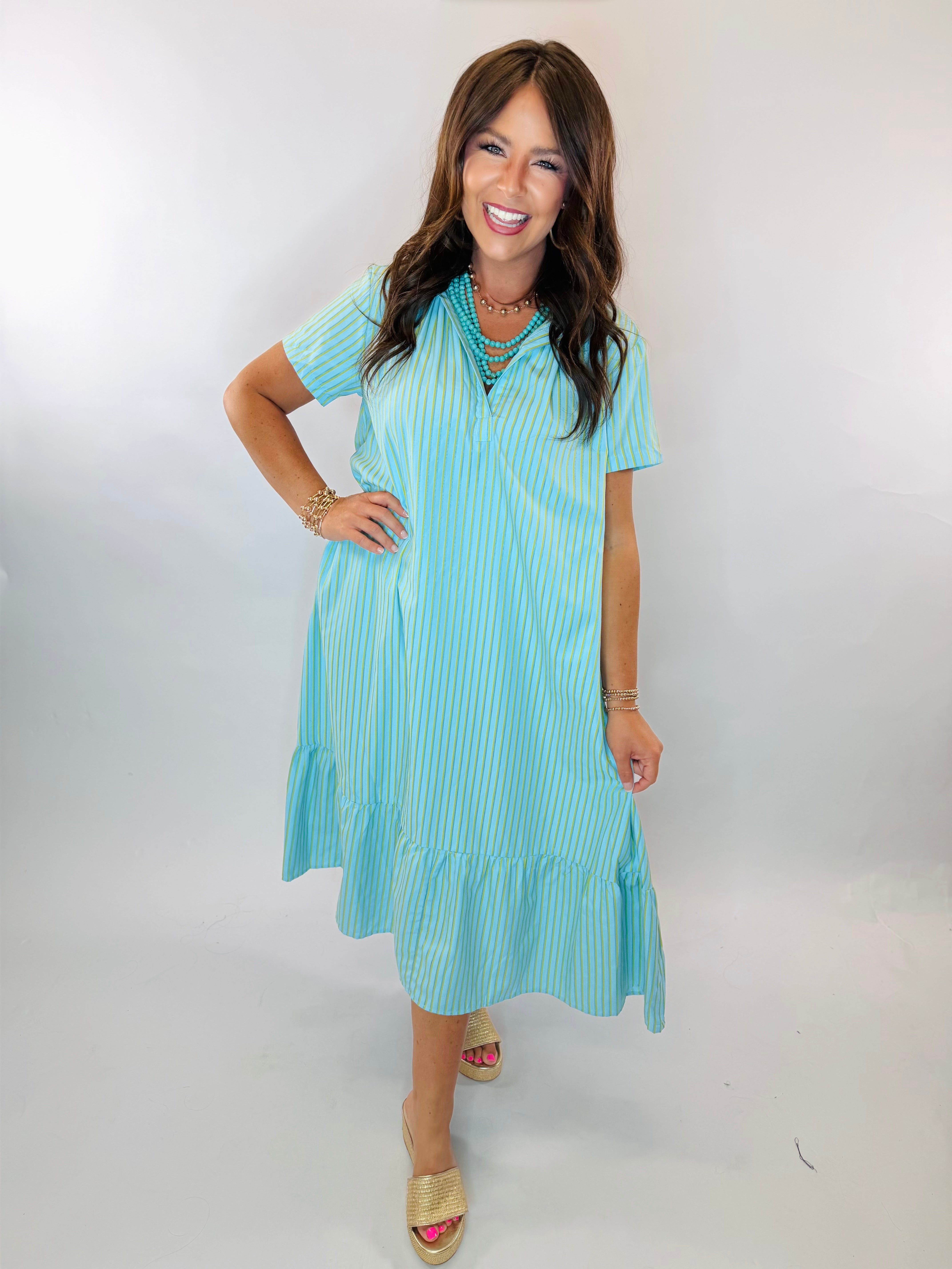 Woman wearing Kate Midi Dress in aqua blue with yellow stripes, ruffle hem, and short sleeves.