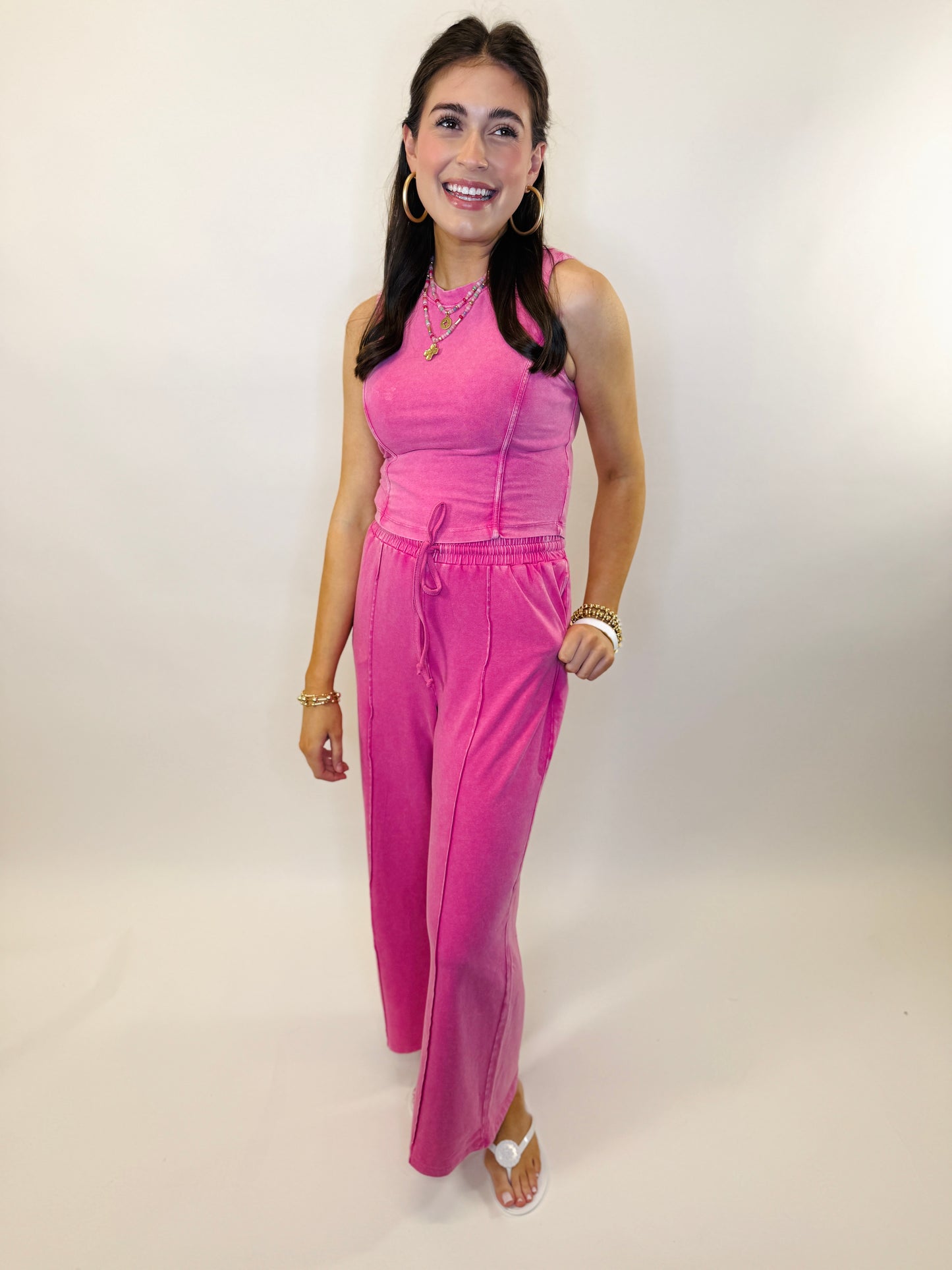 Woman wearing bright pink velour two-piece tracksuit set with corset-style top and wide-leg pants
