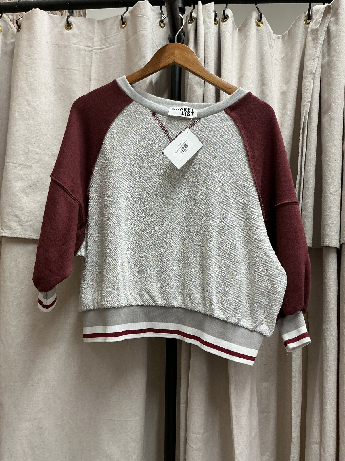 Harriet Top hanging on wooden hanger - gray herringbone fabric with burgundy sleeves and striped ribbed hem