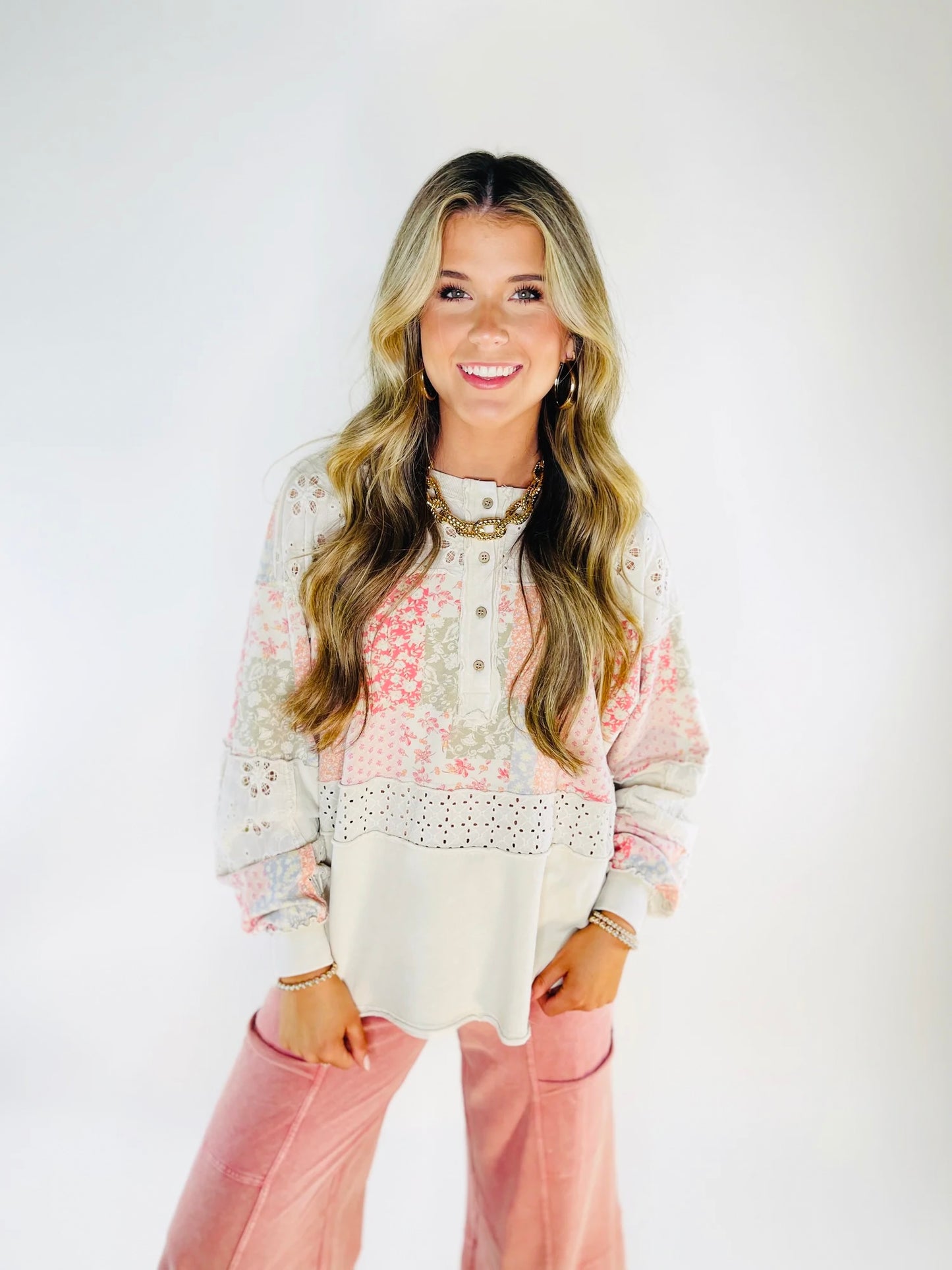 Woman wearing patchwork floral top with eyelet lace details and button front in pink and white tones