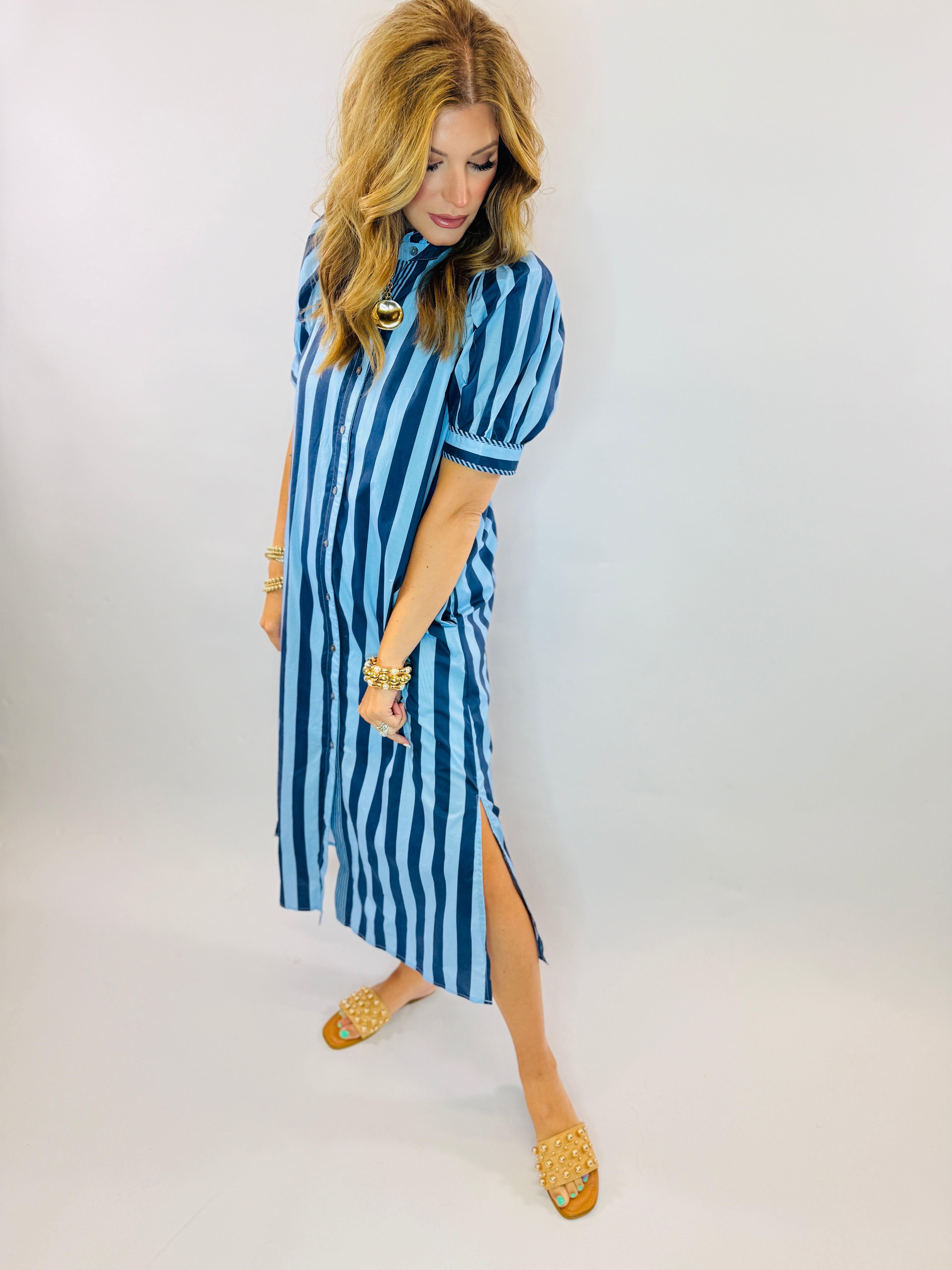 Woman wearing blue and white striped Dora Maxi dress with gold sandals and jewelry accessories.