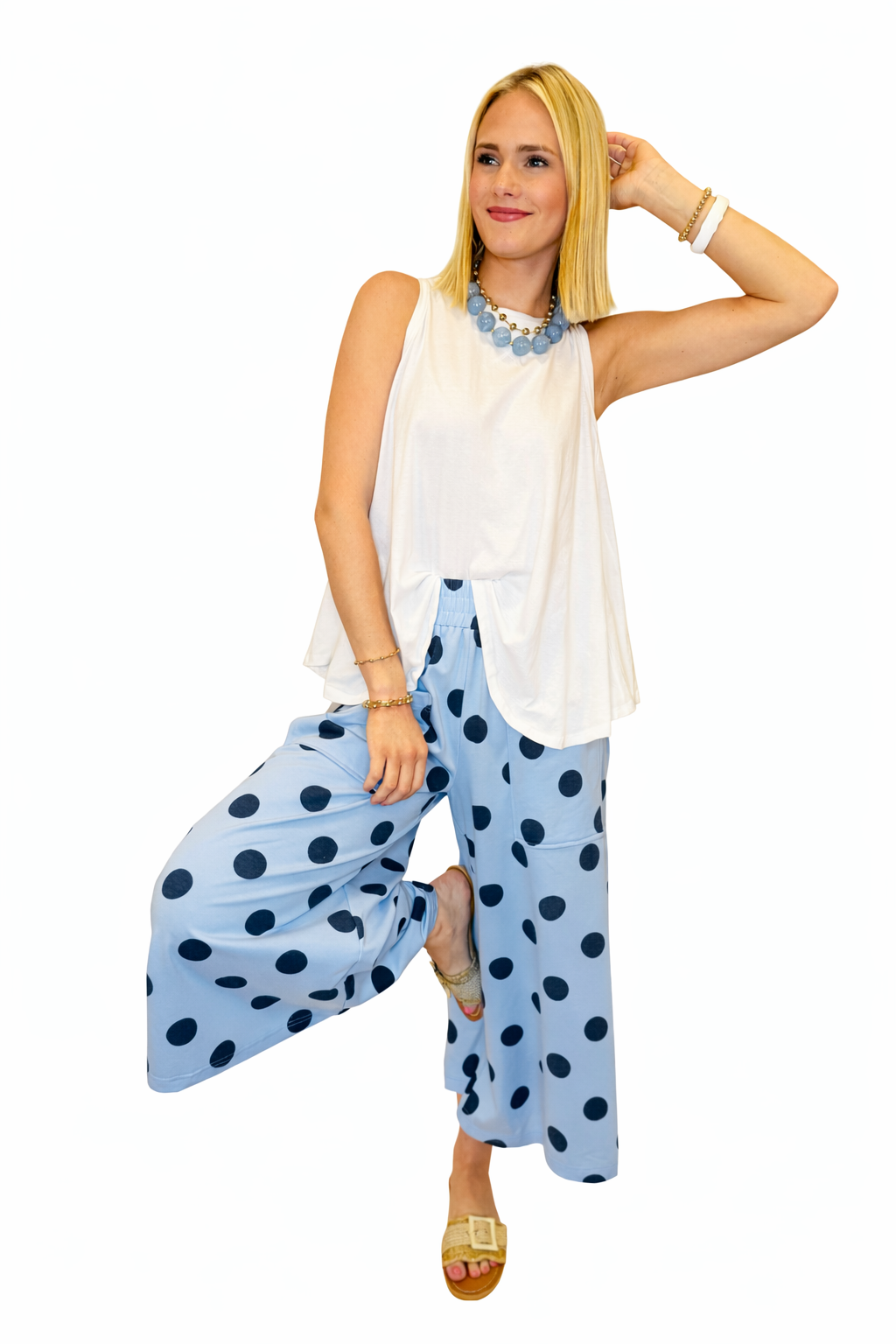 Blonde woman wearing white sleeveless Lacey tank top with blue polka dot wide-leg pants and statement necklace.