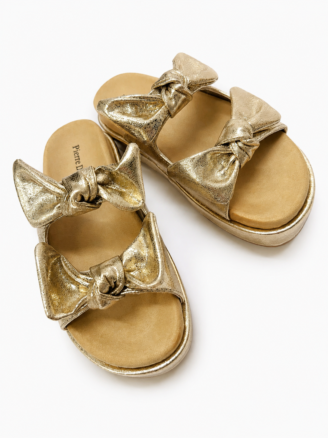 Gold metallic platform sandals with twisted bow details across the front straps.