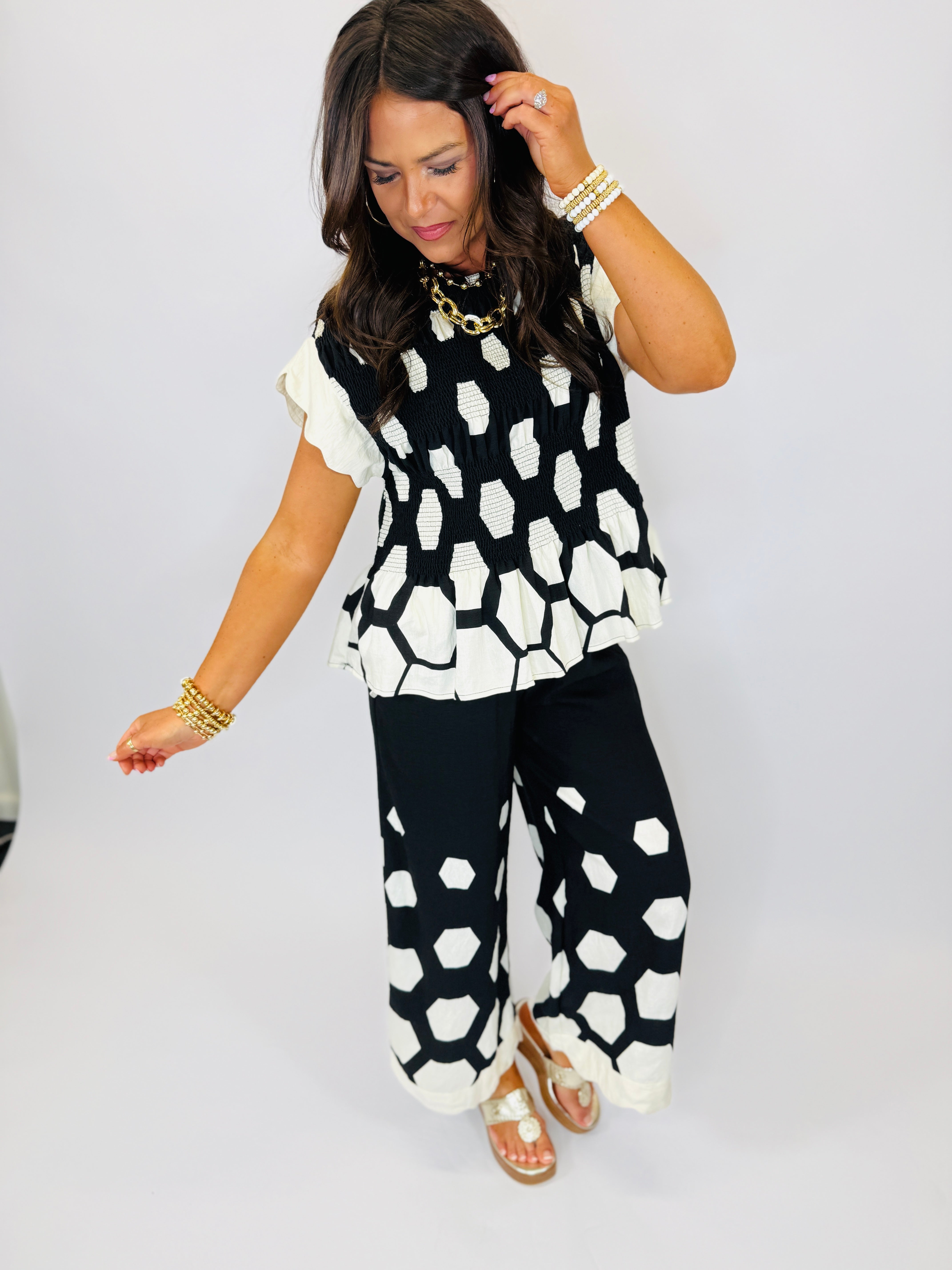 Woman wearing black and white honeycomb patterned Caroline set with ruffled sleeves and matching wide-leg pants