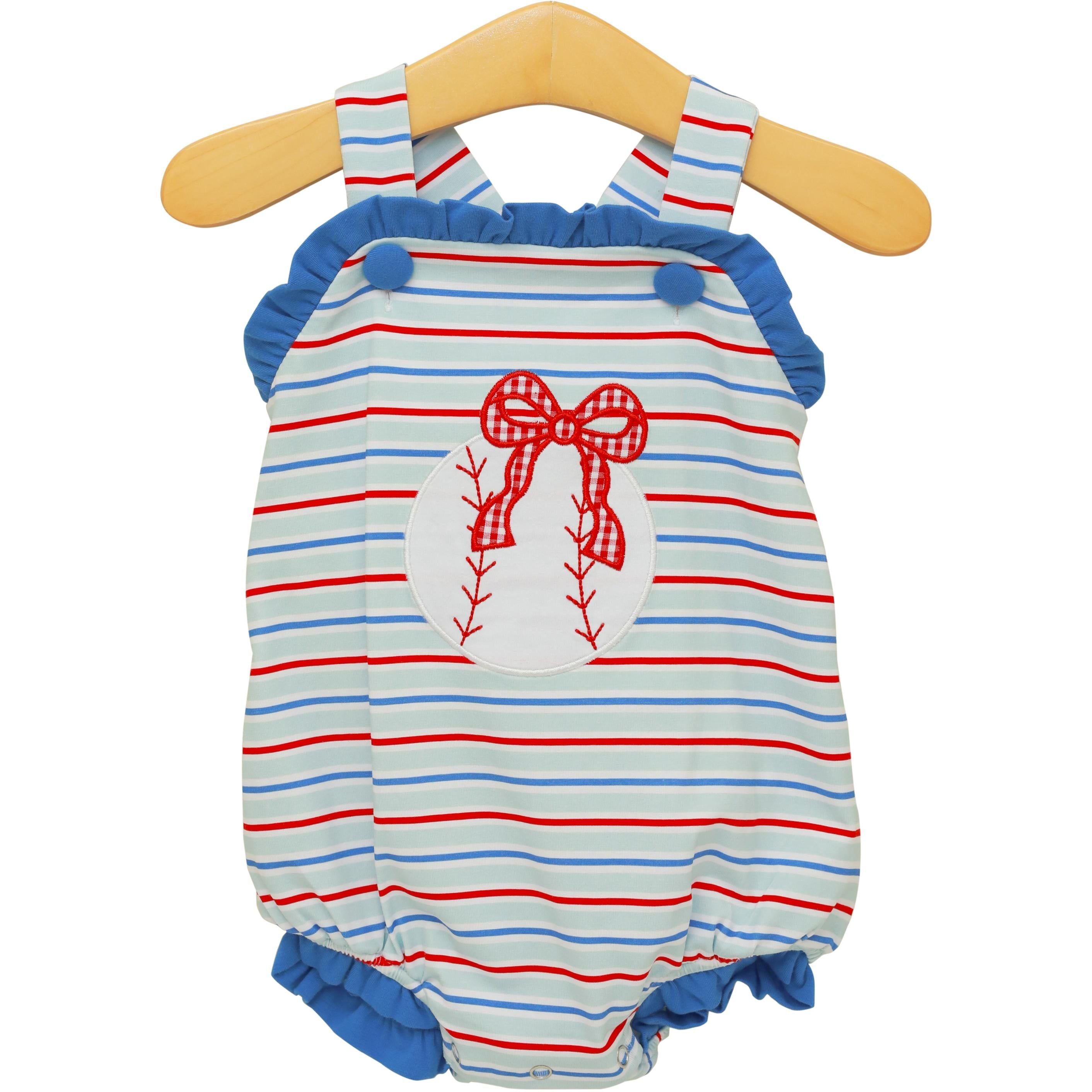 Red, white and blue striped baby sunsuit with baseball and bow applique design on wooden hanger.