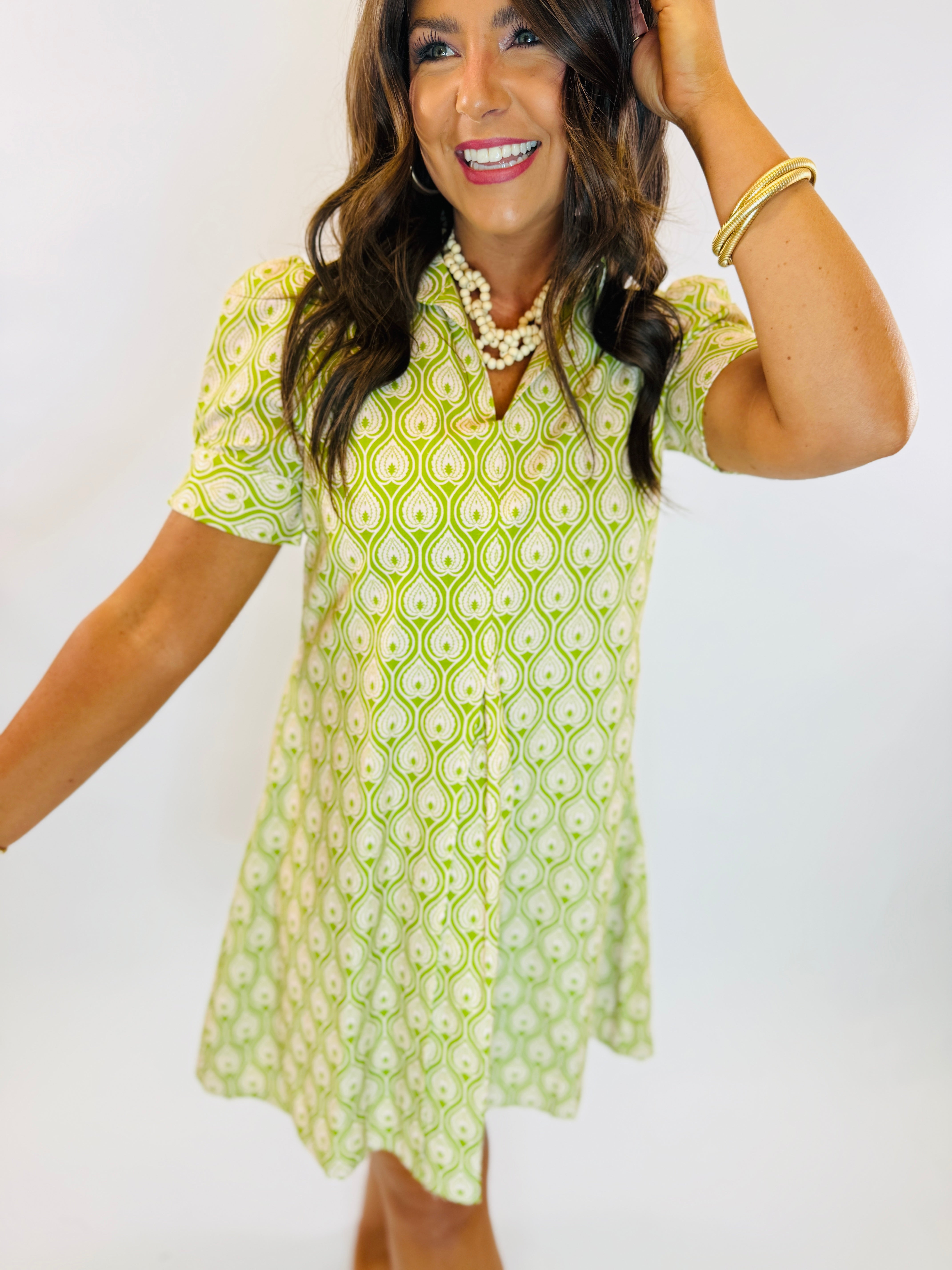 Woman wearing the Lisa Dress in green and white paisley print with short puff sleeves and V-neckline.