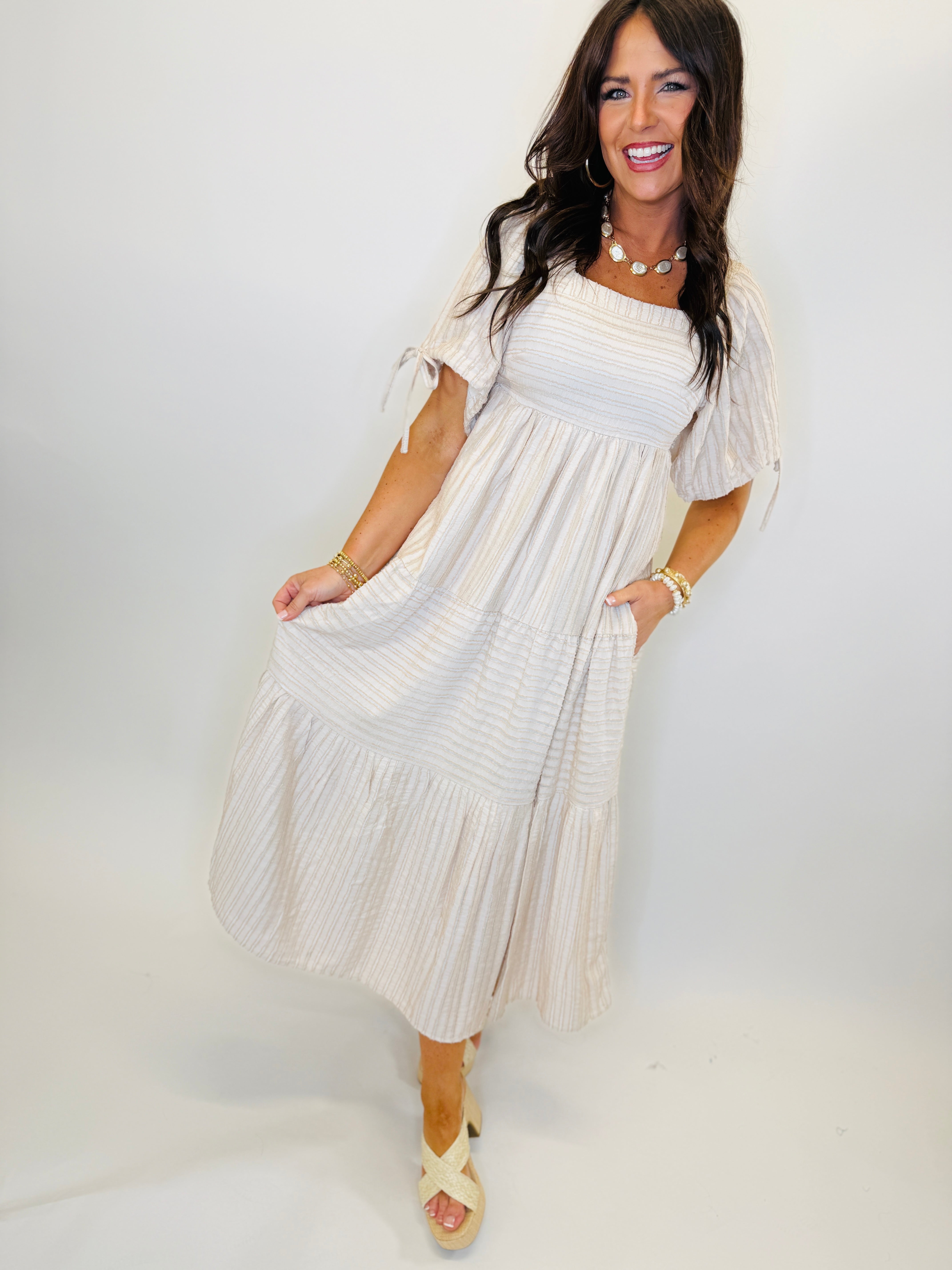 Woman wearing taupe striped off-shoulder maxi dress with tiered ruffle hem and short puff sleeves