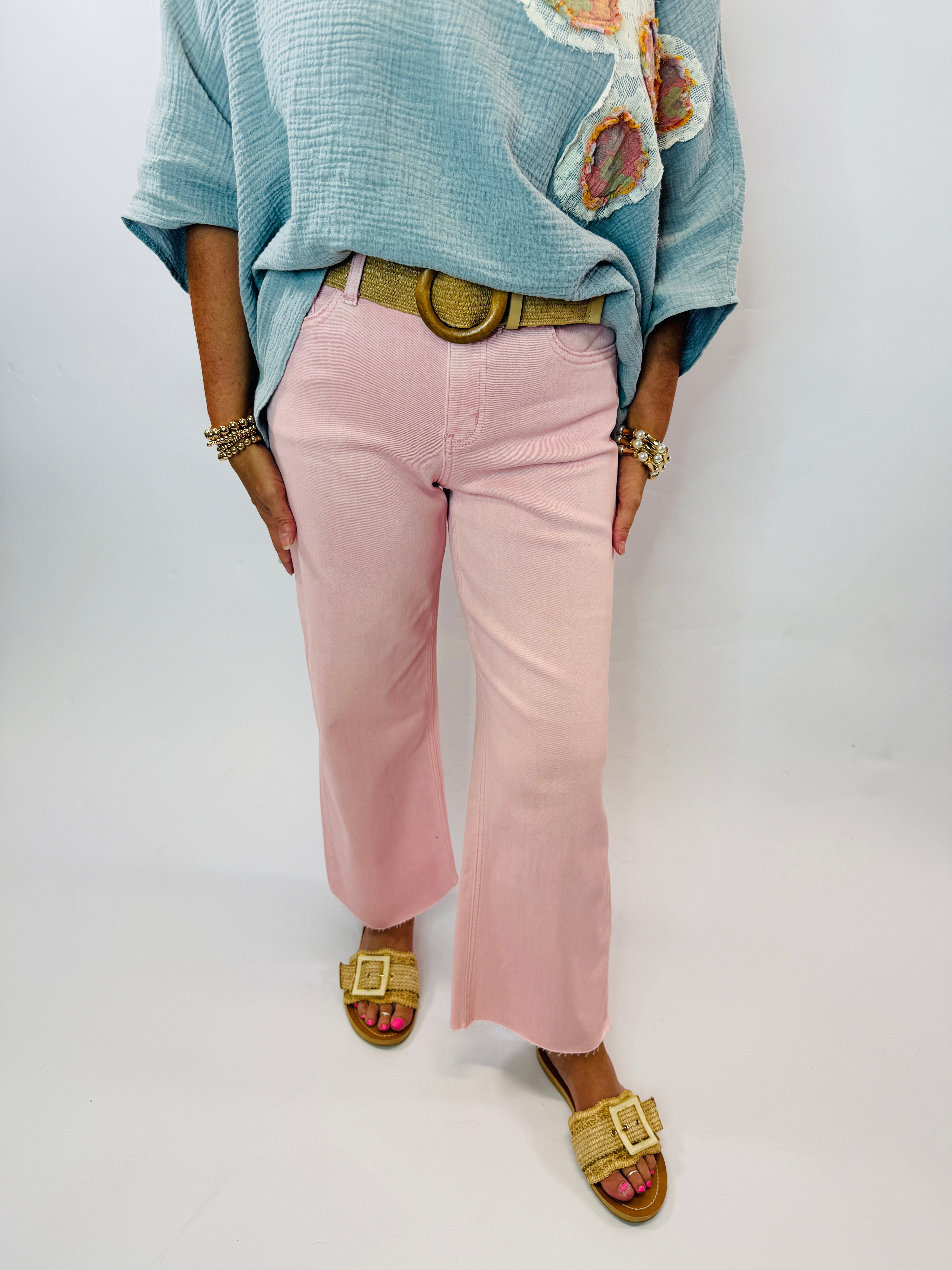 Wide-leg pink pants worn with light blue top, gold belt, and woven sandals in casual styling
