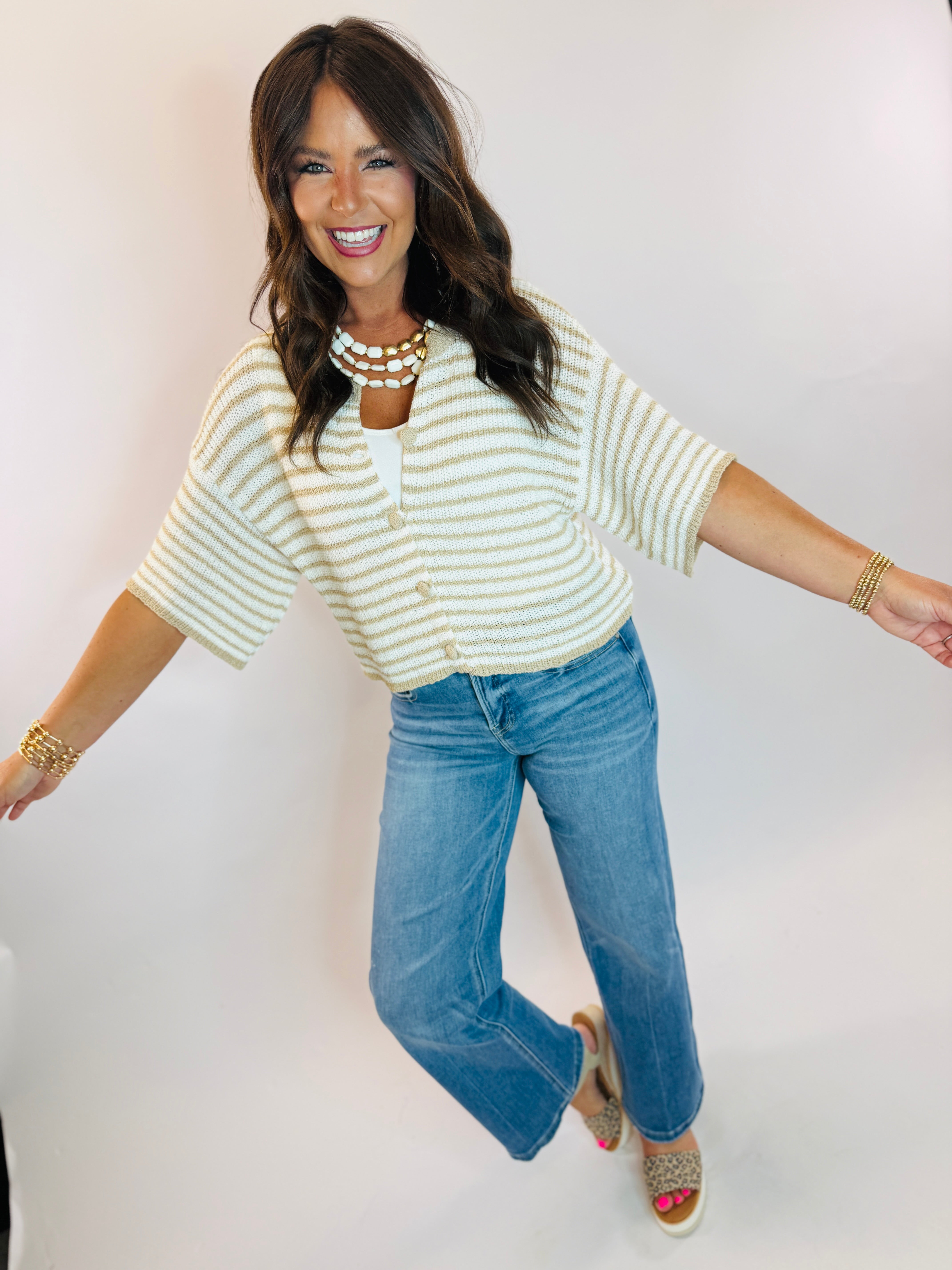 Woman wearing striped cream and tan knit cardigan top with short sleeves and button front detail.