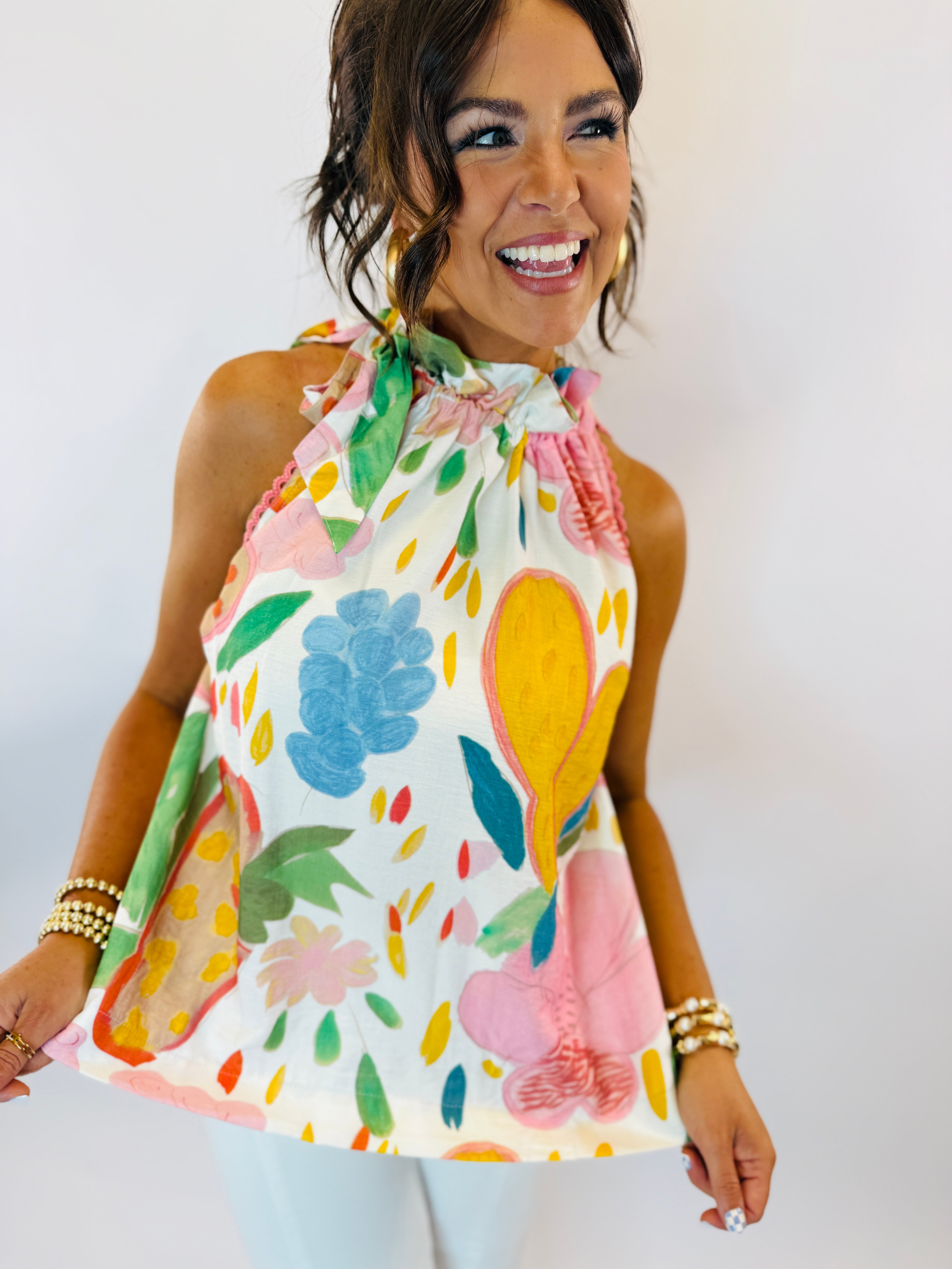Woman wearing colorful floral halter top with tie neck detail and vibrant botanical print on white background