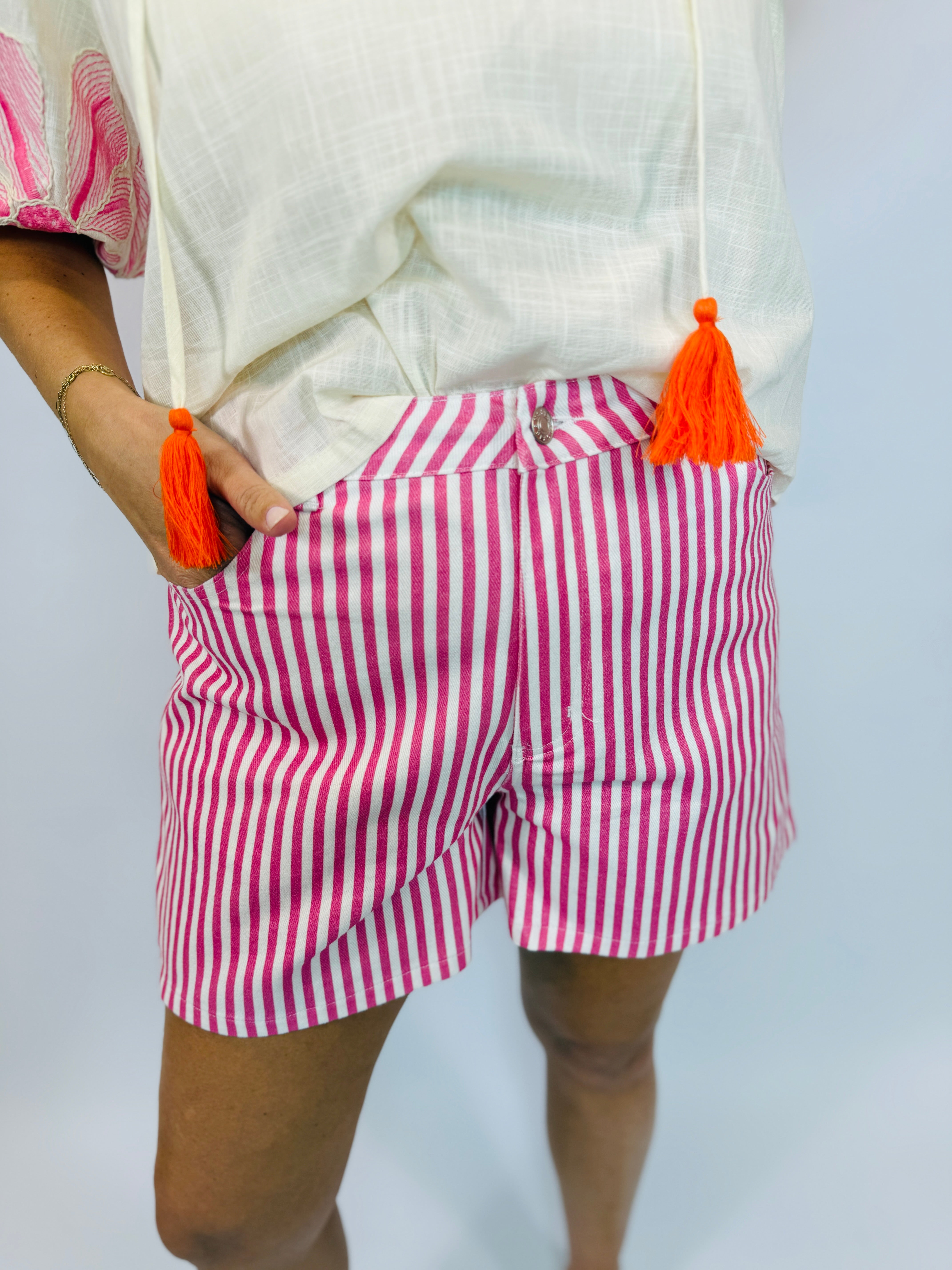 Pink and white striped Daphne shorts with orange tassel drawstrings and matching top detail.