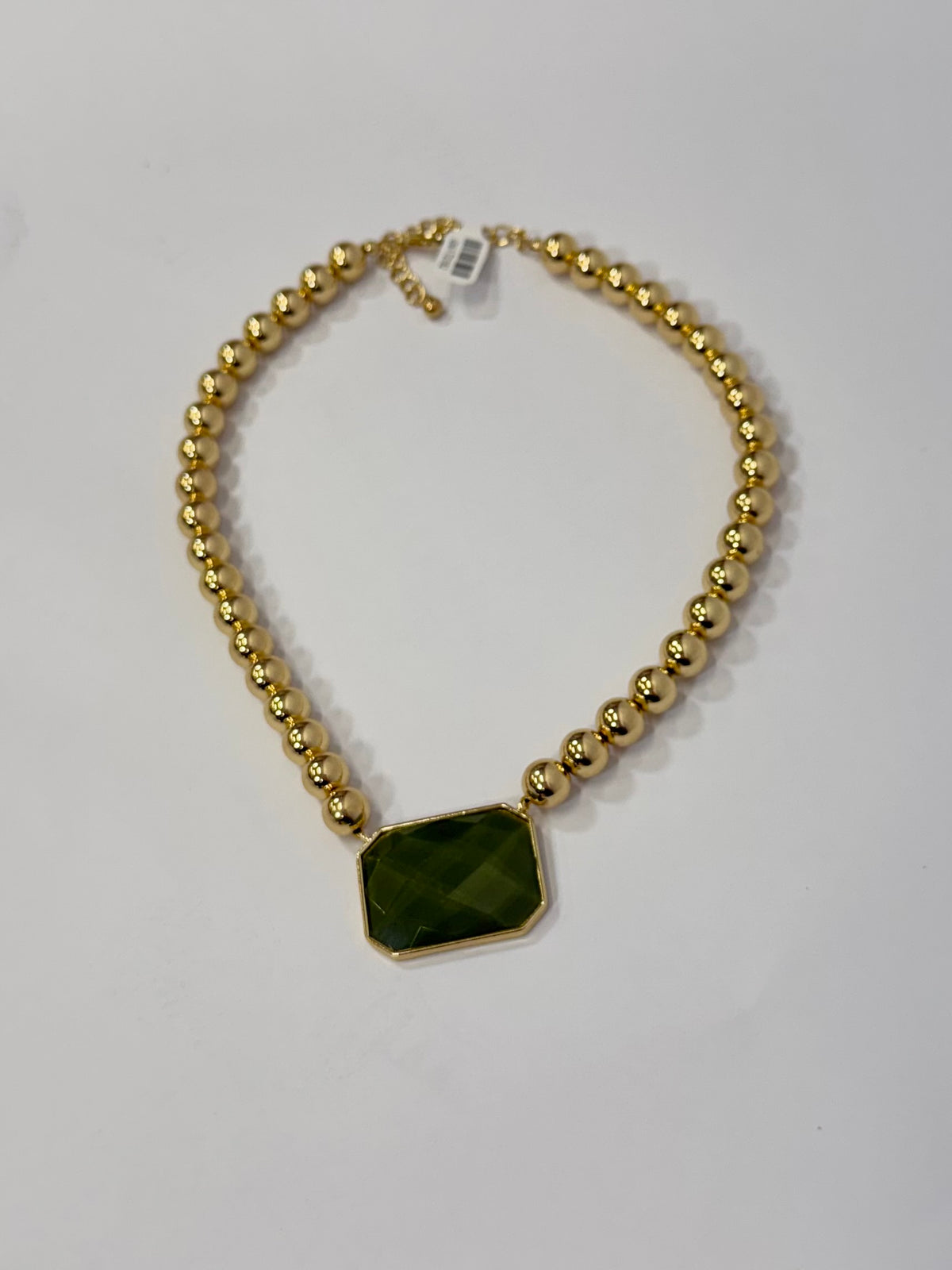 Gold beaded necklace with large faceted olive green rectangular pendant stone centerpiece on white background.