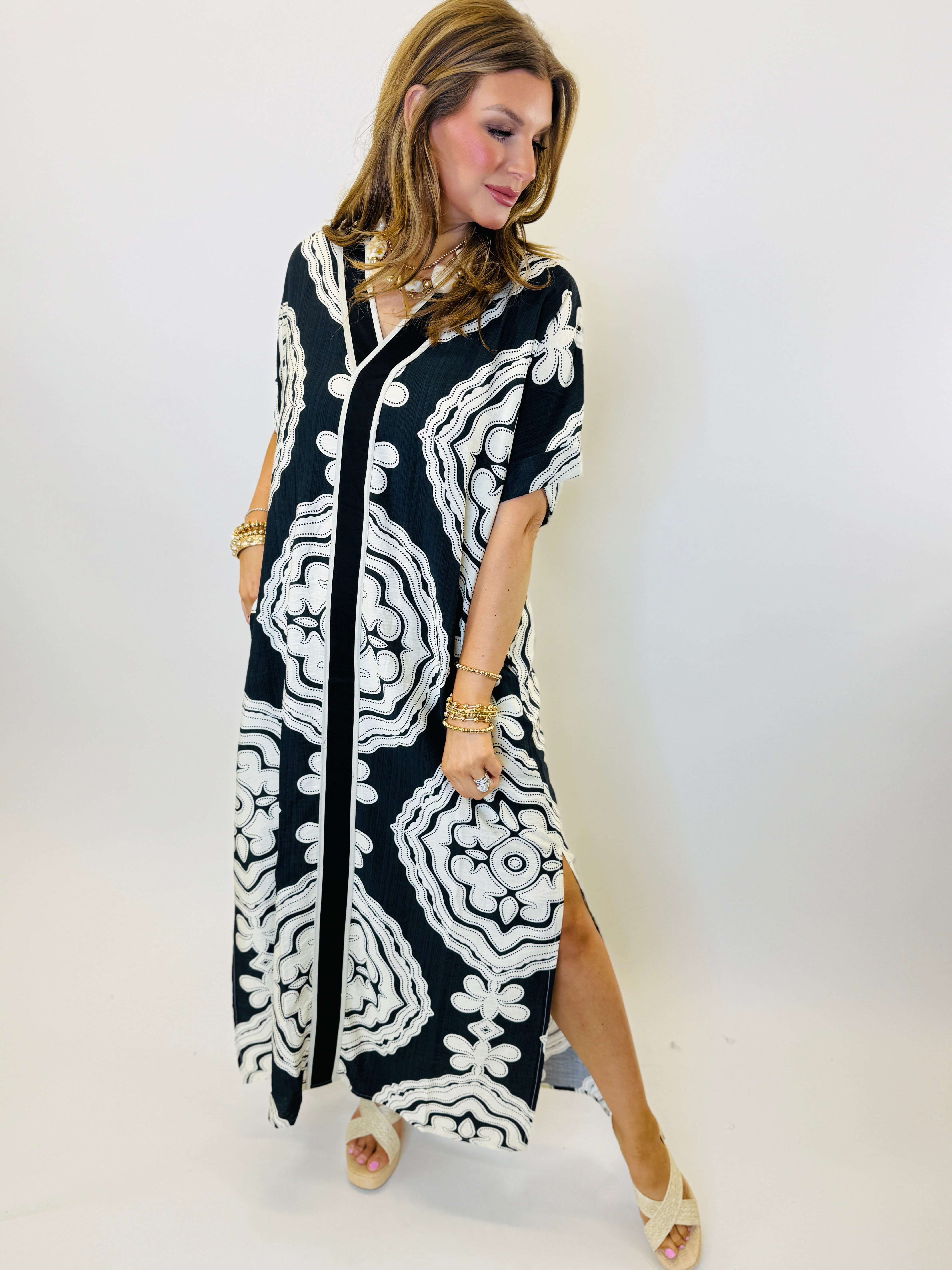 Woman wearing black and white patterned maxi dress with geometric floral print and three-quarter sleeves