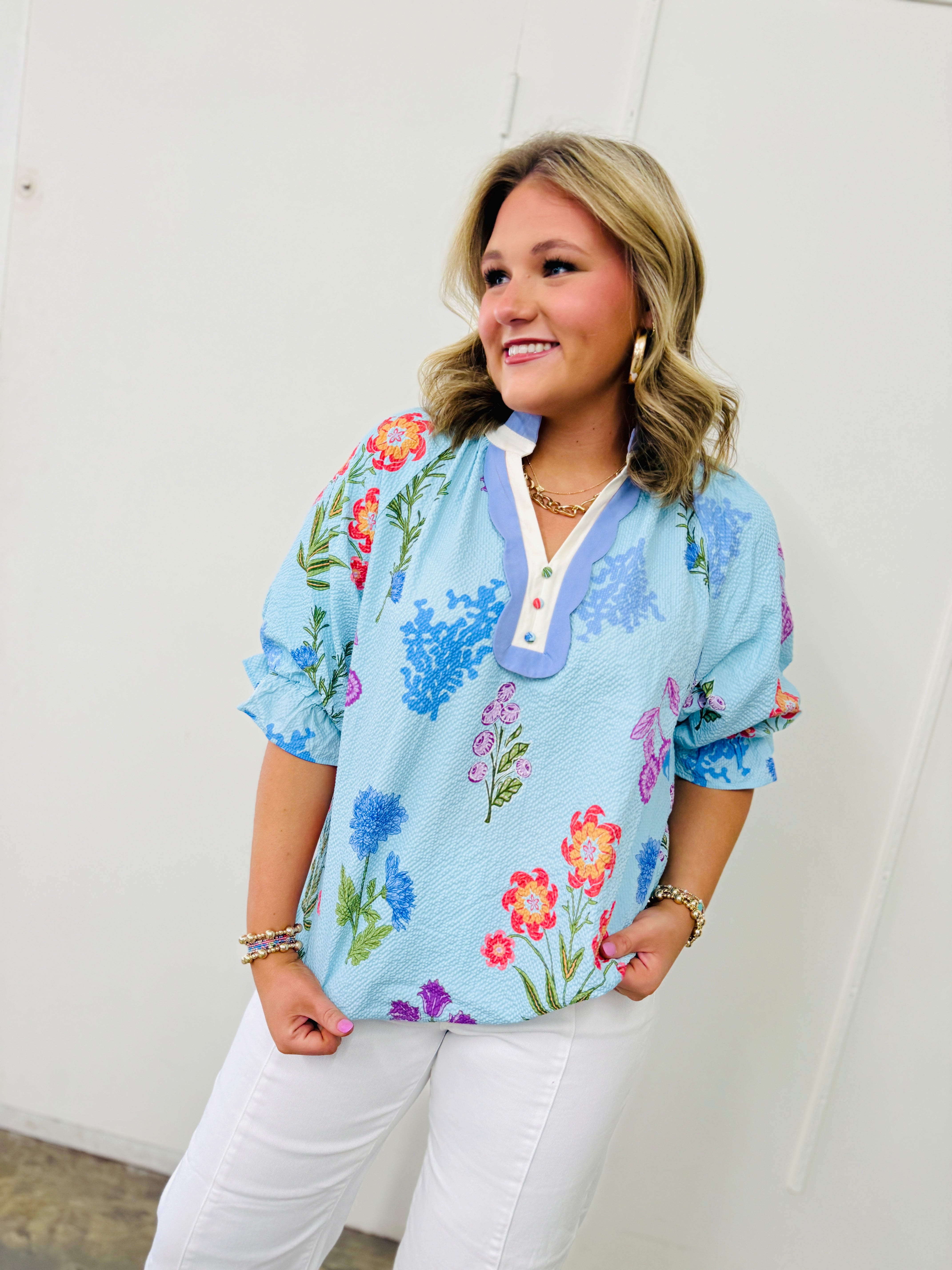 Light blue floral blouse with colorful flower print, short sleeves, and white collar detail on model