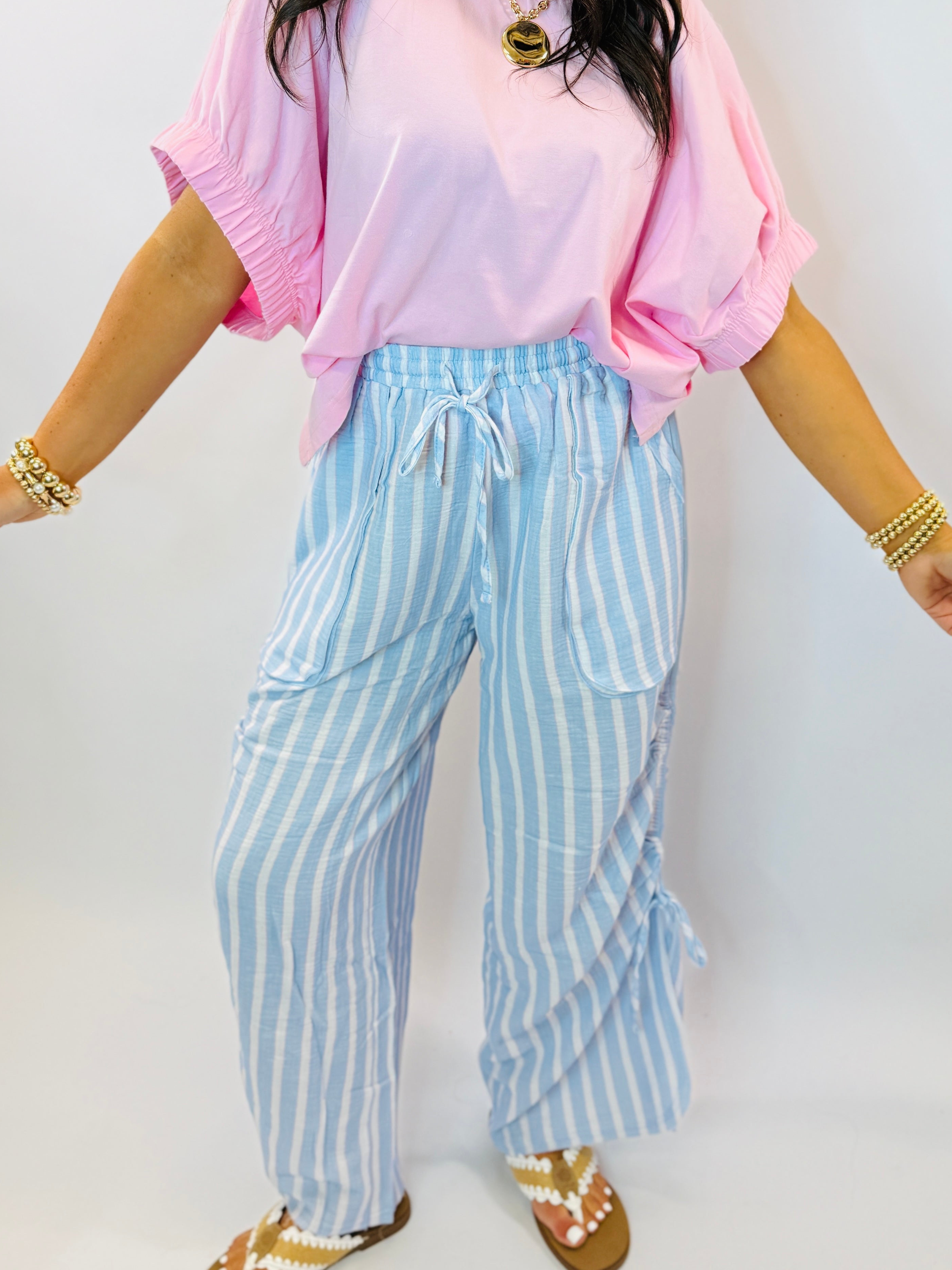 Woman wearing blue and white striped wide-leg pants with drawstring waist and side pockets, paired with pink top.
