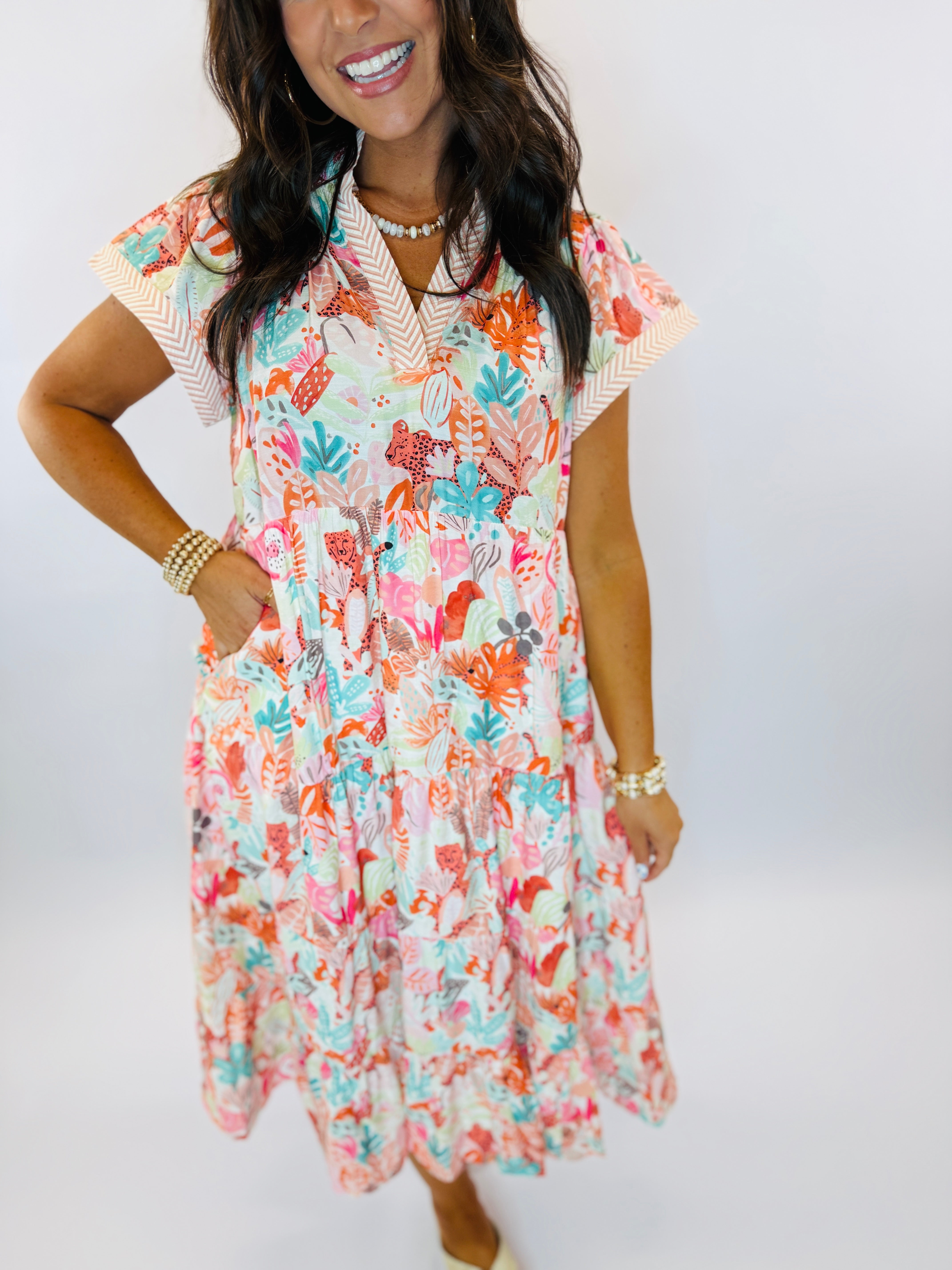 Woman wearing colorful floral Lexie dress with short sleeves, tiered skirt, and tropical print pattern