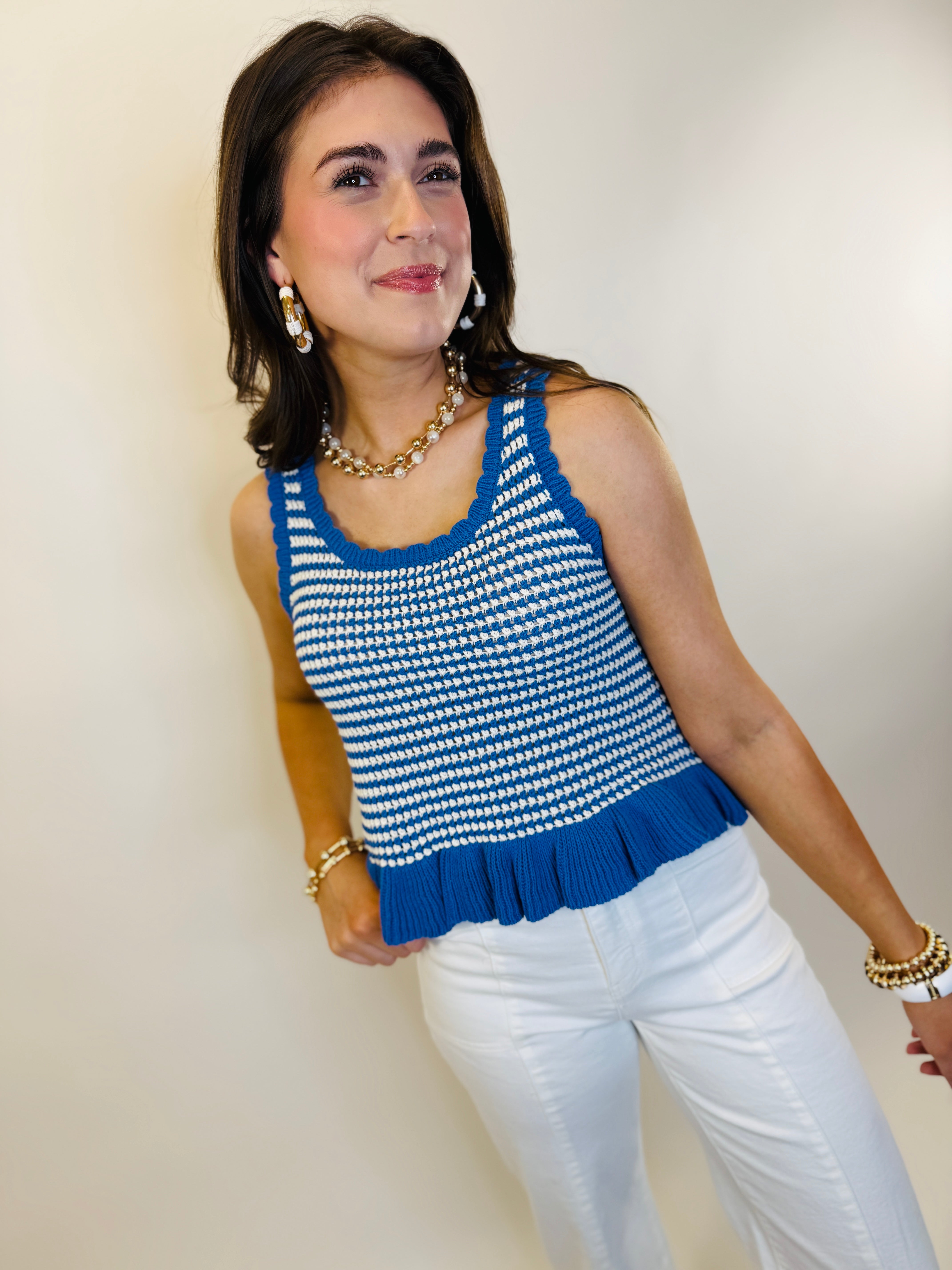 Woman wearing blue and white striped knit tank top with white pants and pearl jewelry