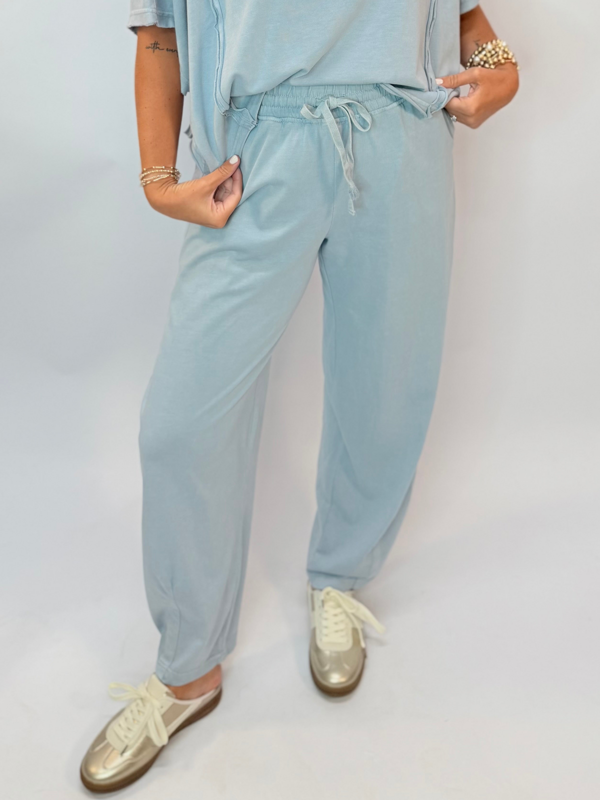 Light blue drawstring jogger pants with elastic waistband, paired with metallic sneakers.