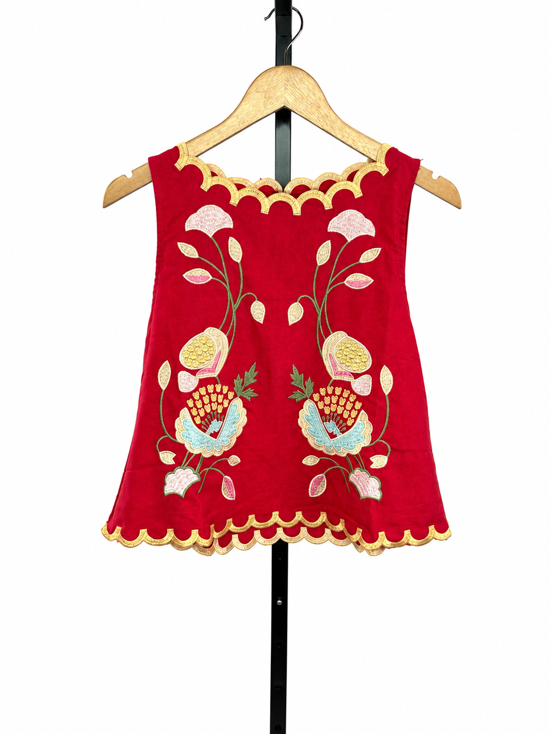 Red sleeveless Alexa Top with multicolor floral embroidery and gold scalloped hem details on hanger.