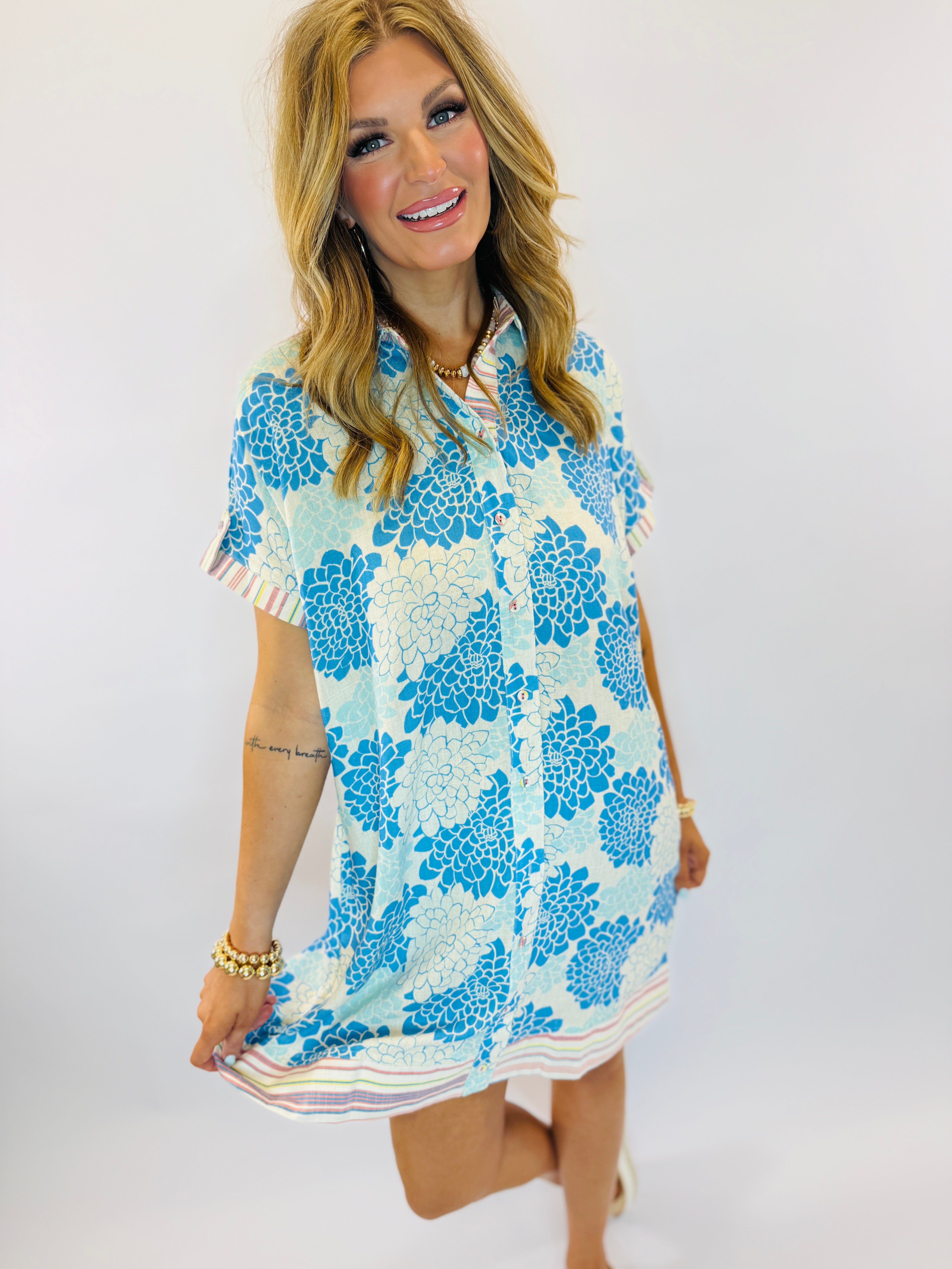 Woman wearing blue and white floral print short-sleeve dress with striped trim and collar detail