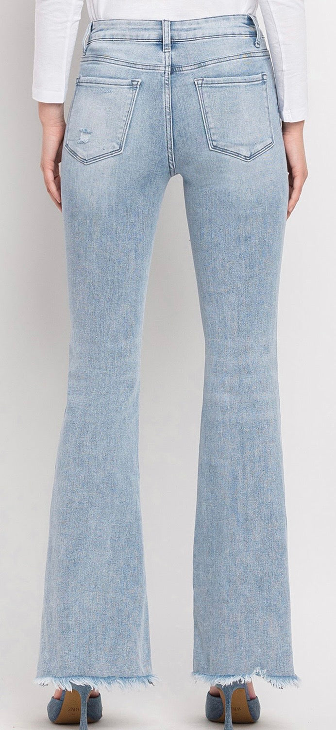 Light wash flare jeans with frayed hem shown from behind on model wearing white top