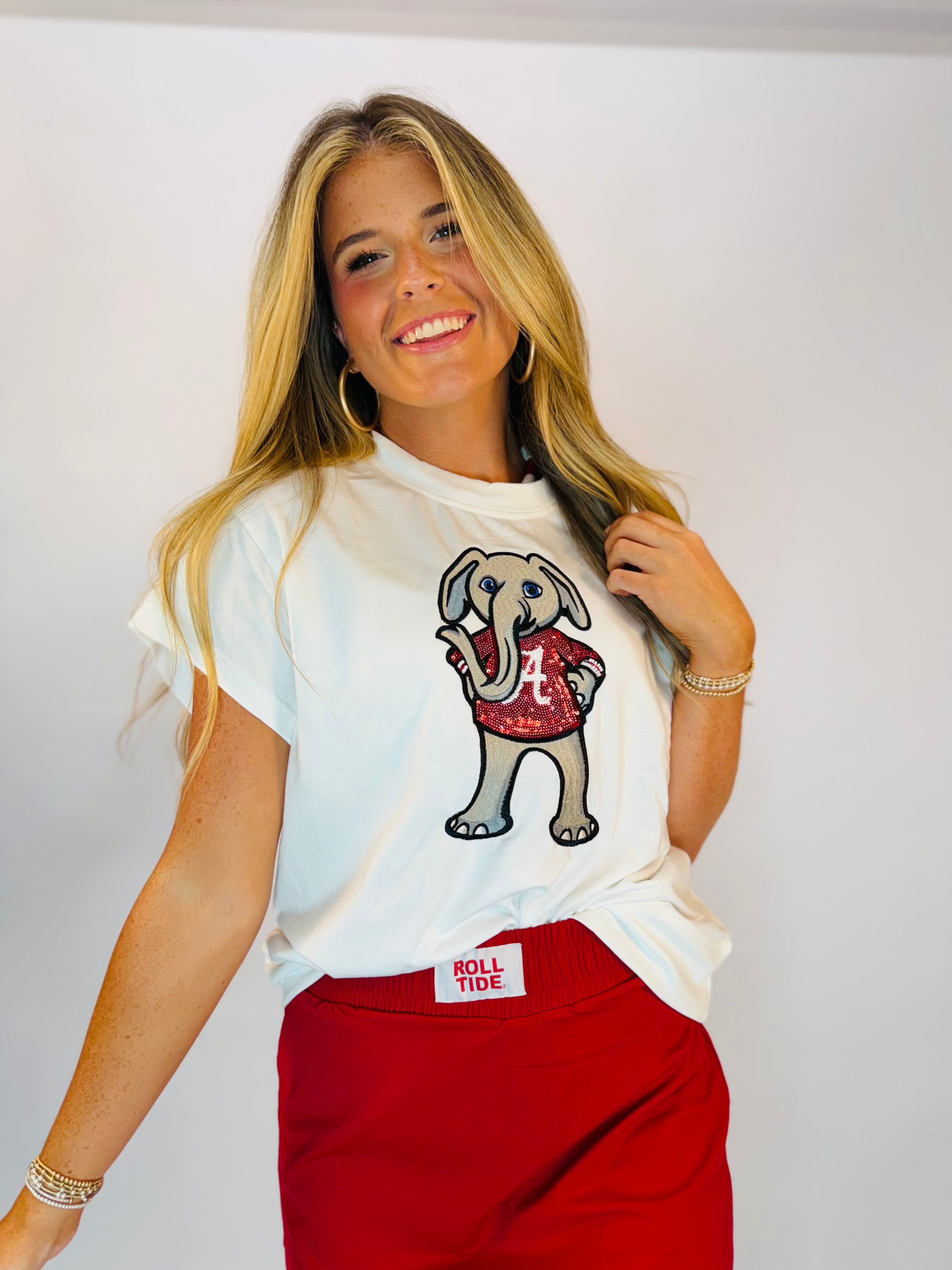 White University of Alabama t-shirt featuring rhinestone Big Al elephant mascot graphic, styled with red Roll Tide shorts.