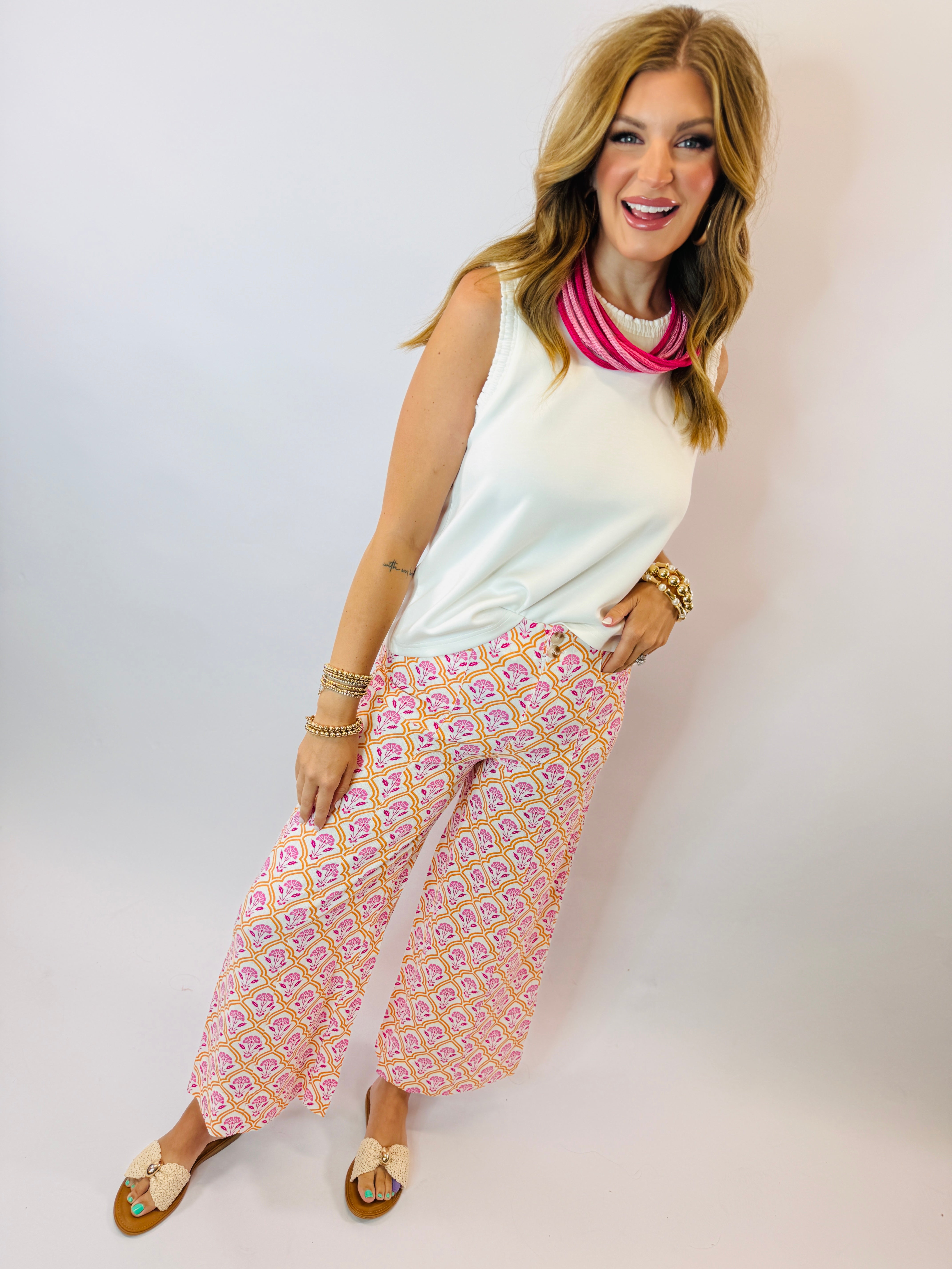 Woman wearing off-white sleeveless Georgie top with pink patterned wide-leg pants and colorful accessories.