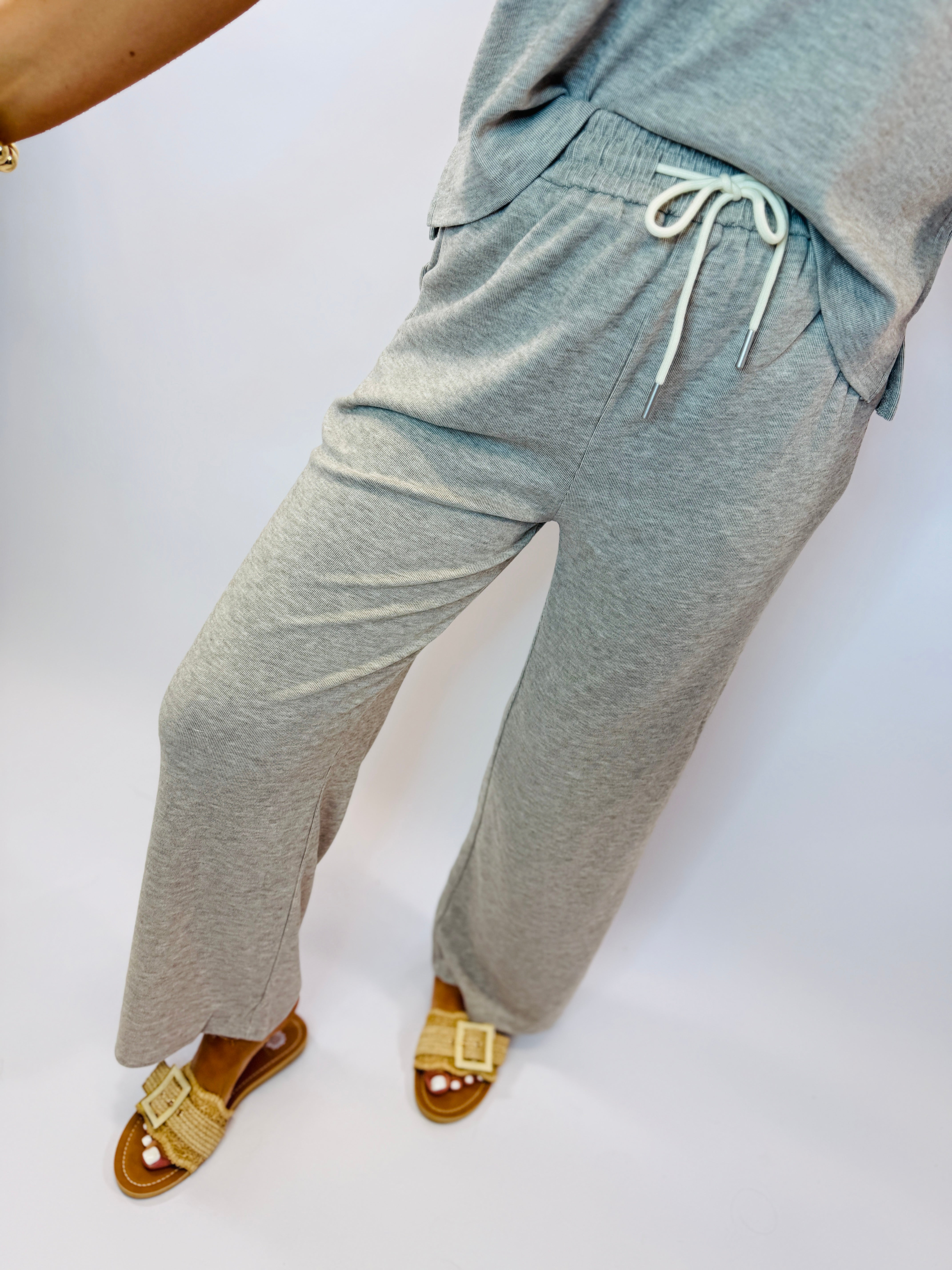 Gray heathered sweatpants with drawstring waist and side pockets, worn with tan woven sandals