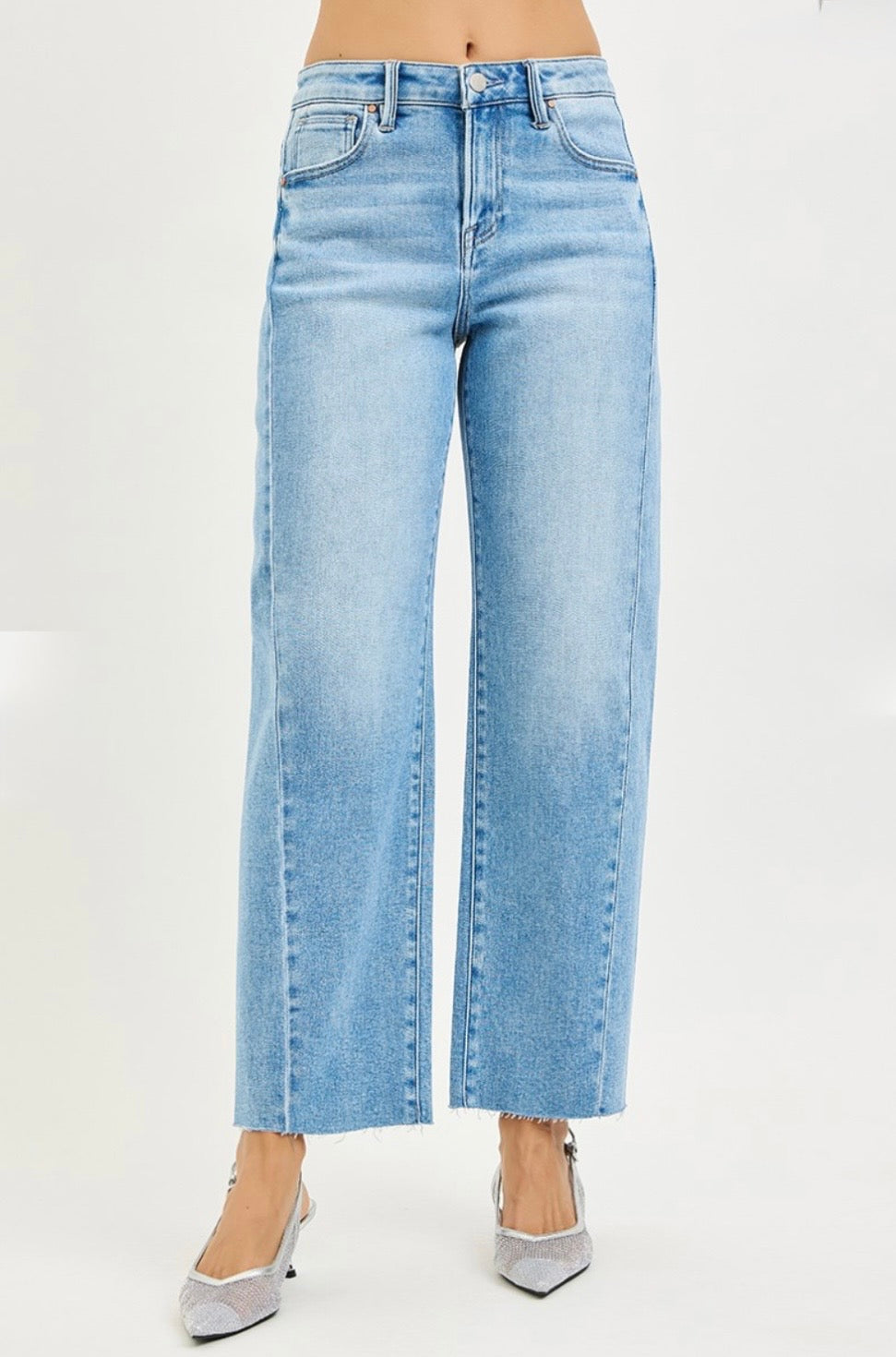 Light blue wide-leg barrel jeans with high waist and raw hem, worn with silver pointed-toe heels.
