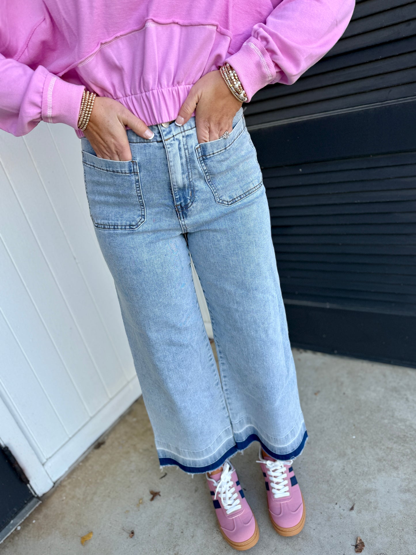 Light wash wide-leg Jana jeans with navy contrast hem detail, styled with pink sweatshirt and sneakers.