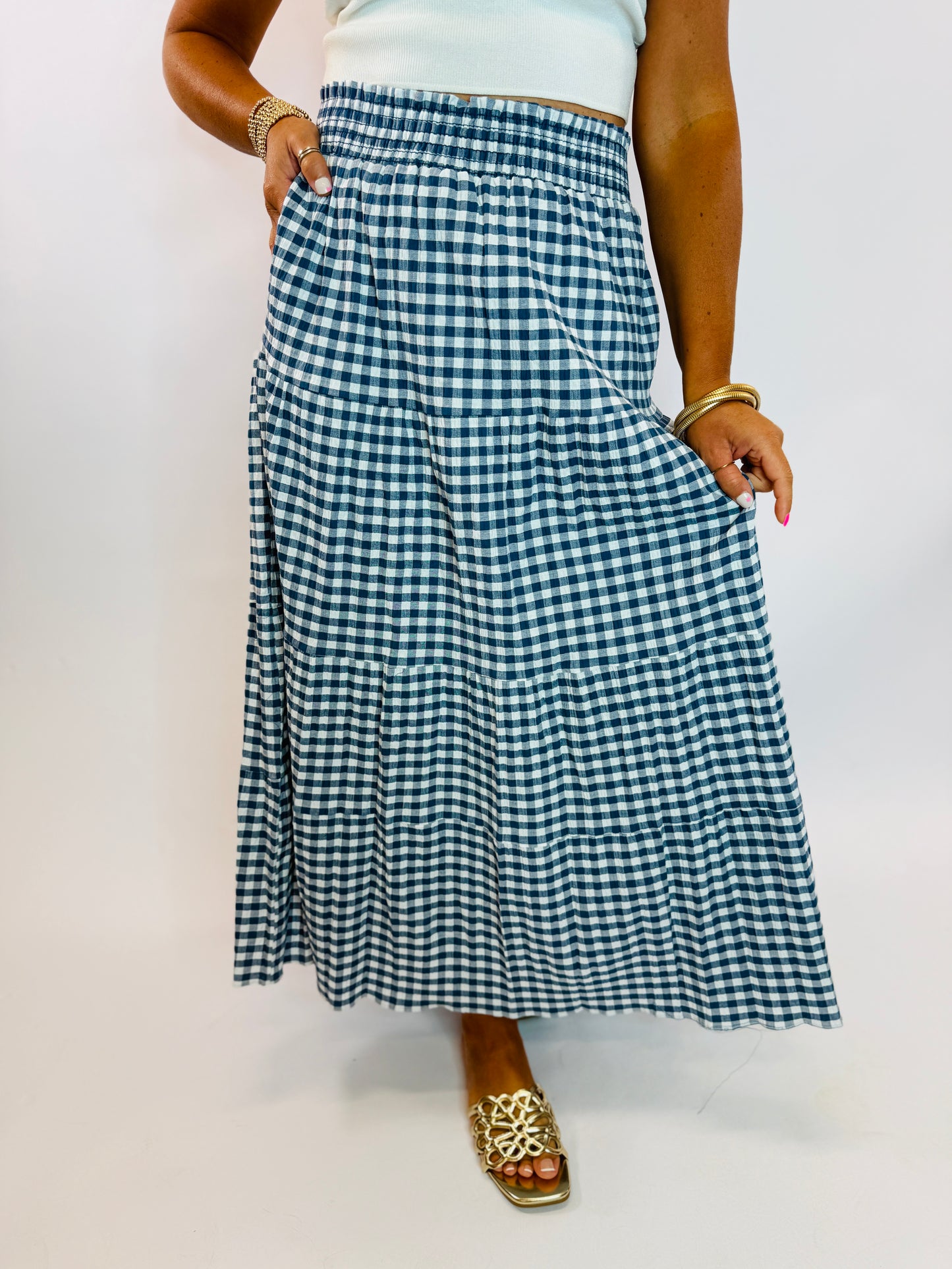 Navy and white gingham tiered maxi skirt with smocked elastic waistband, styled with gold sandals.