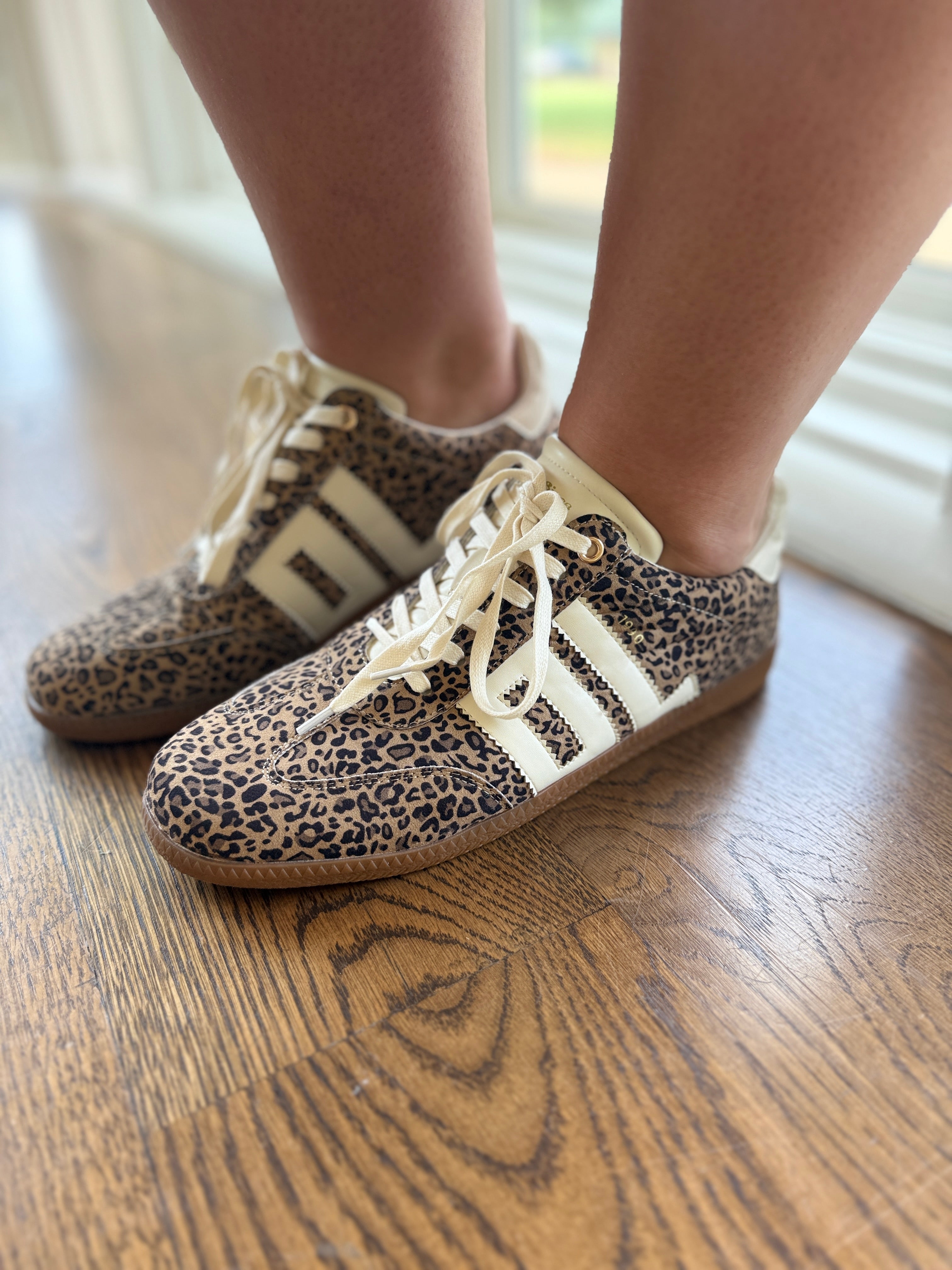 Leopard print Emma sneakers with white laces and cream stripes on wooden floor