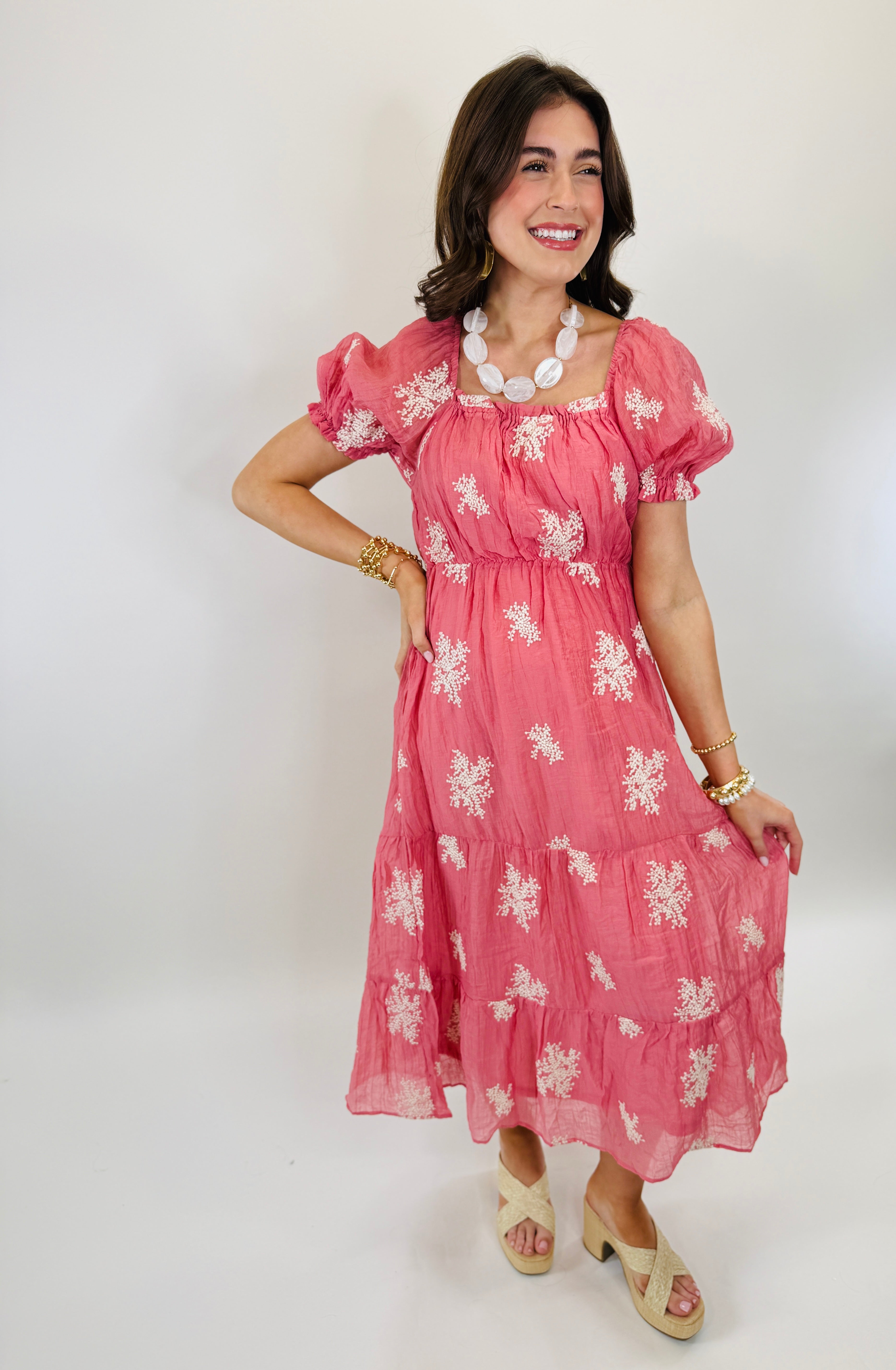 Woman wearing pink floral Averie dress with puffed sleeves, square neckline, and tiered midi-length skirt