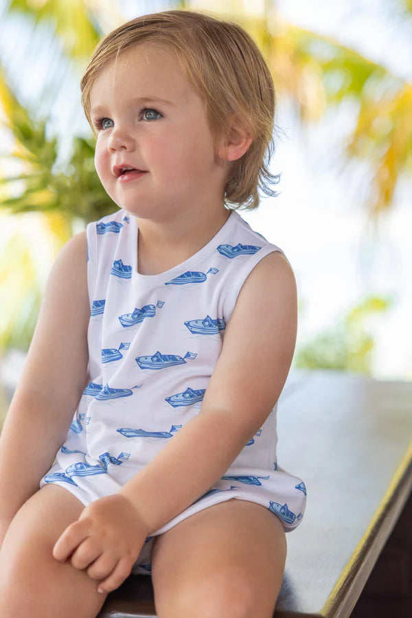 Toddler wearing white sleeveless bubble romper with blue boat print pattern sitting outdoors