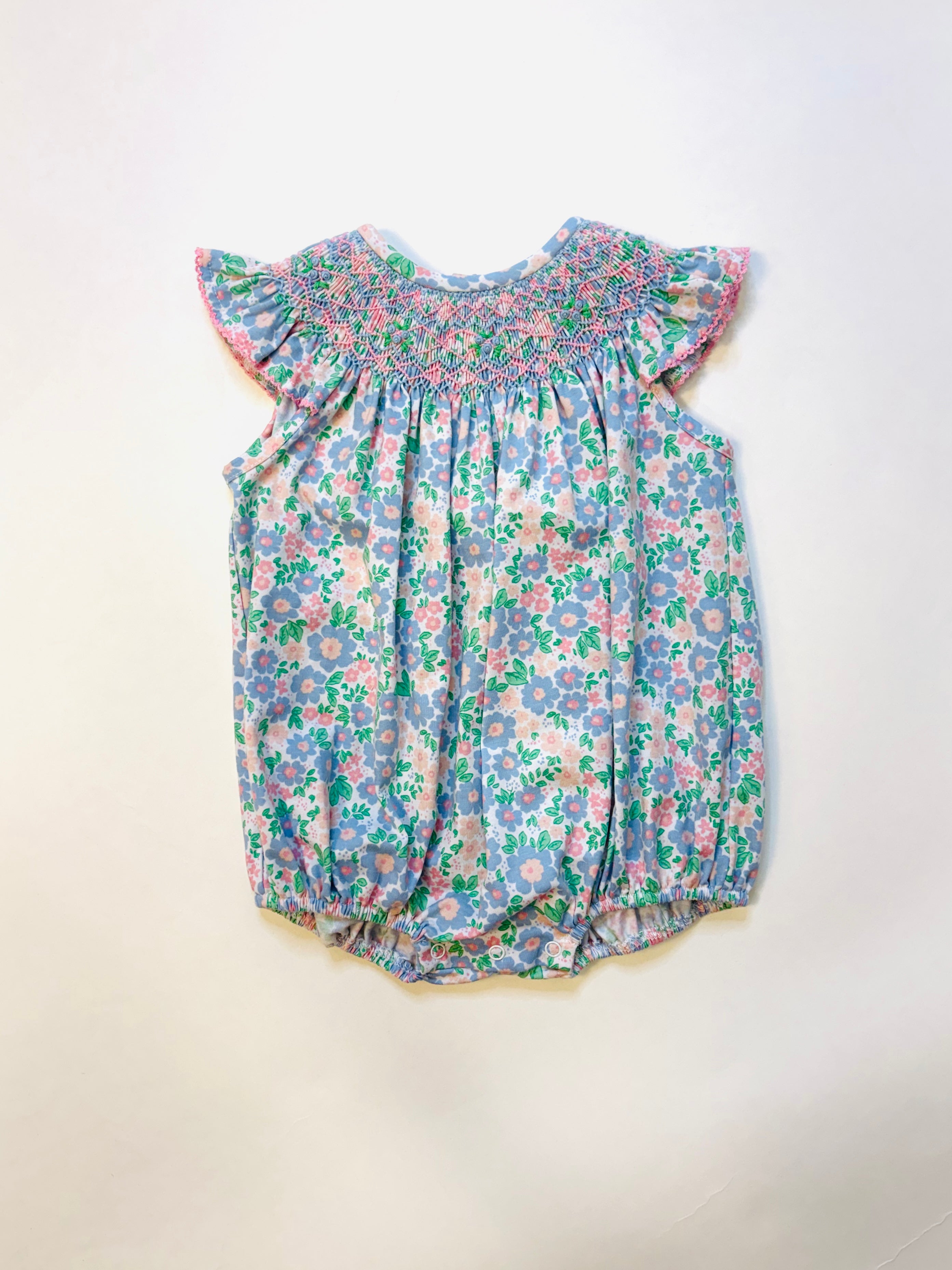 Baby floral romper with smocked neckline, flutter sleeves, and daisy print in blue, pink, and green colors.