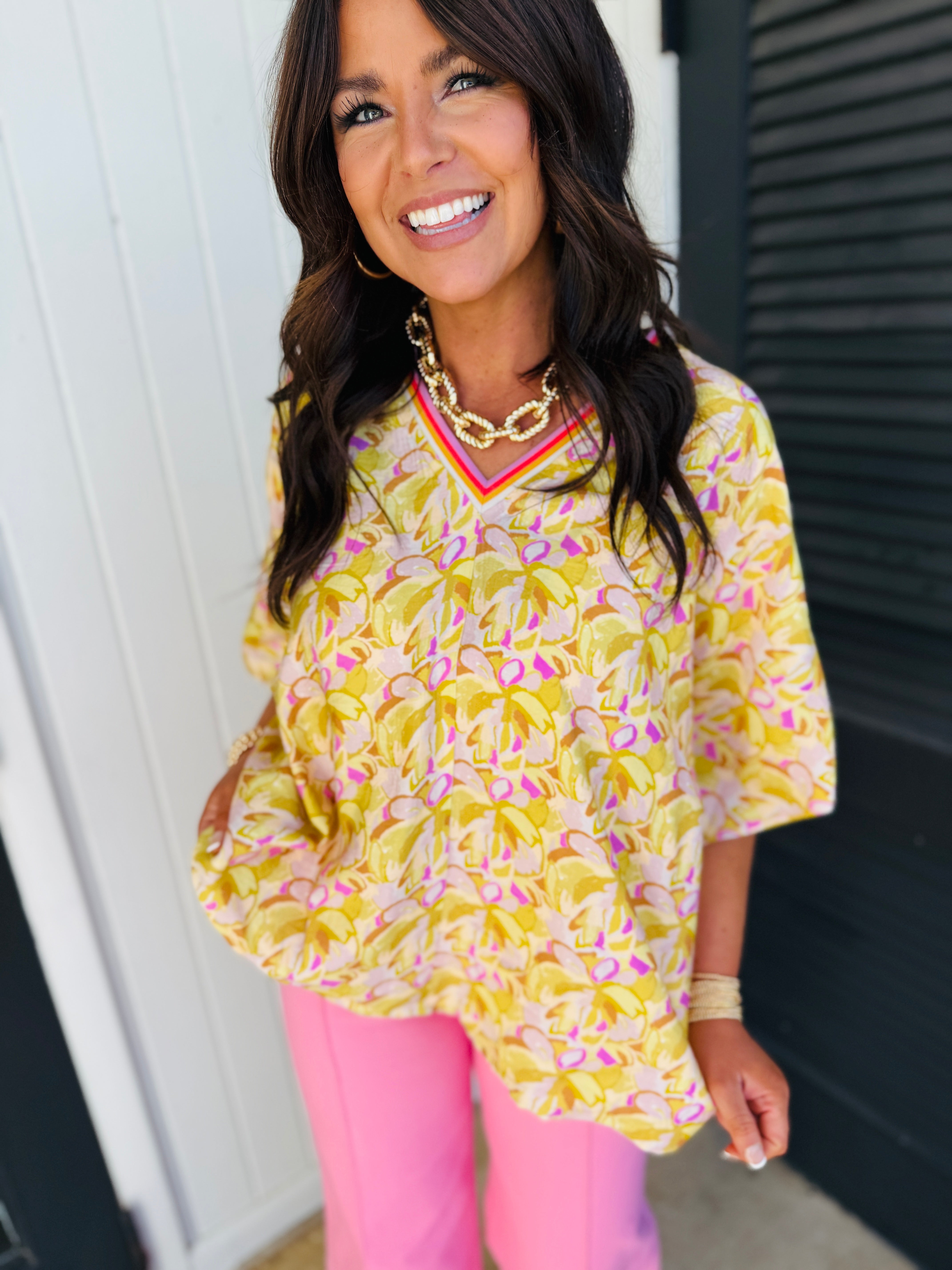 Woman wearing yellow and pink floral patterned Arabella Harper soft top with v-neck and three-quarter sleeves