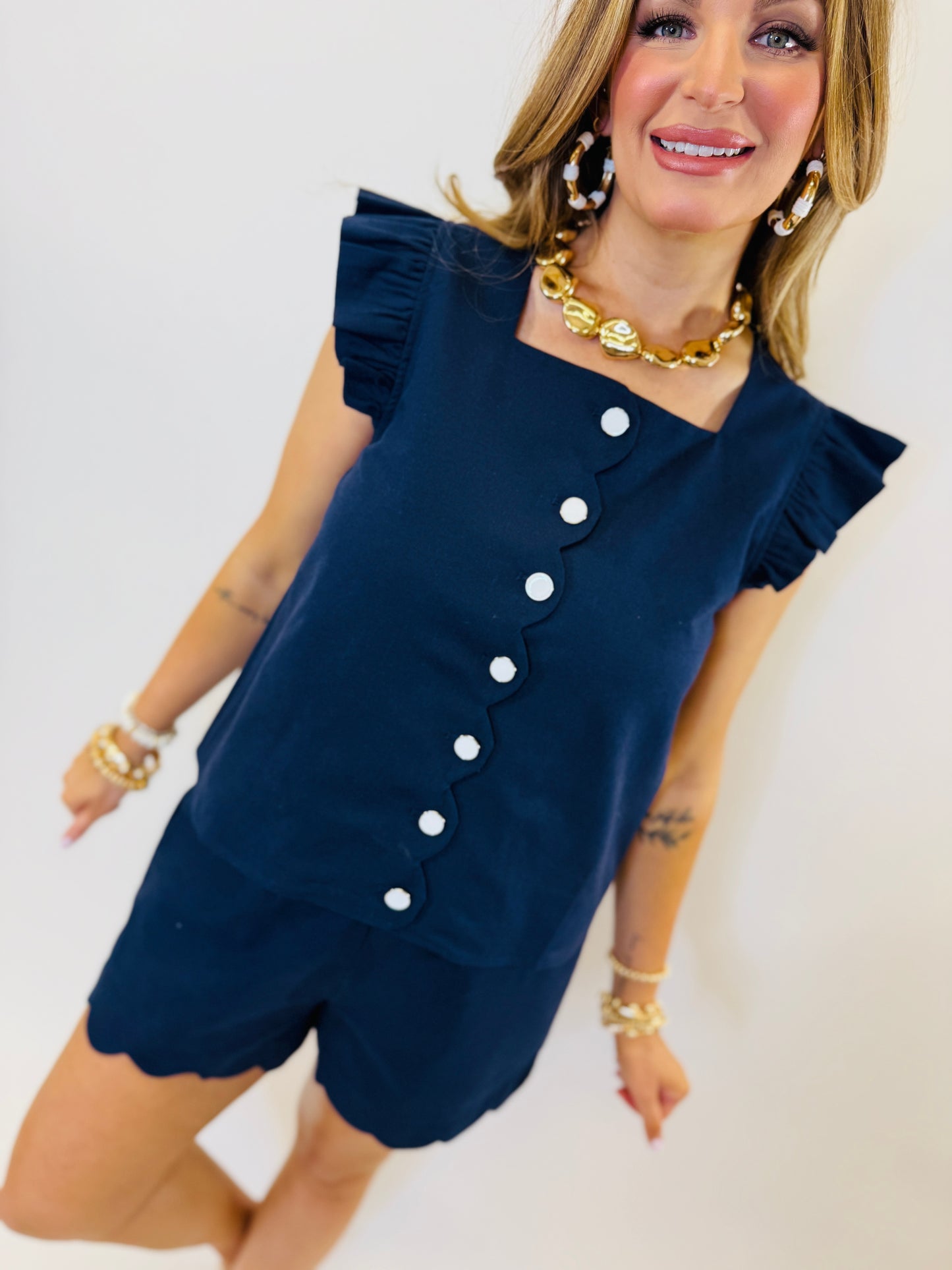 Navy blue ruffle sleeve top with white button front detail and asymmetrical neckline