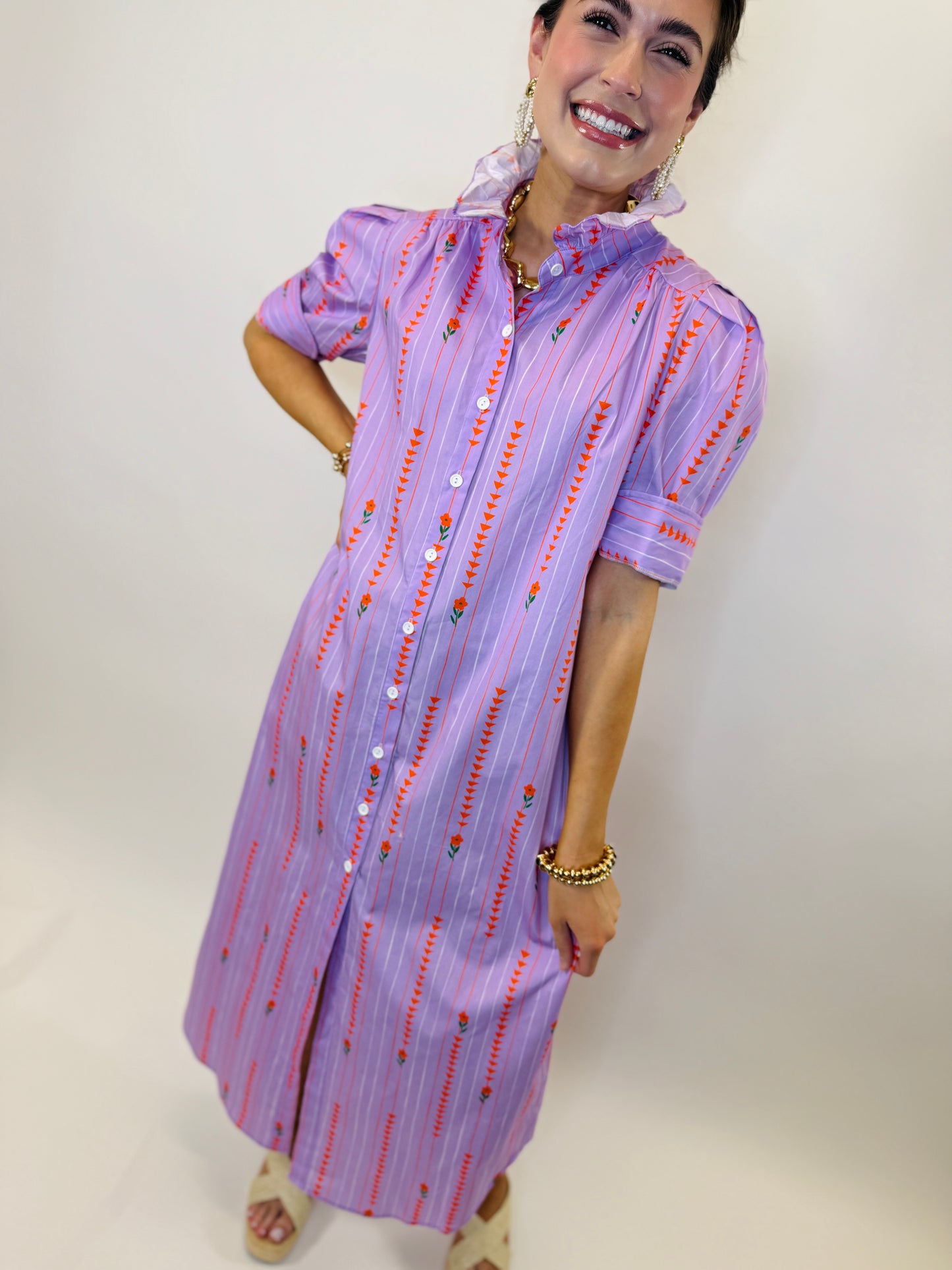 Woman wearing purple striped button-down shirt dress with red floral embroidery and ruffle collar details.