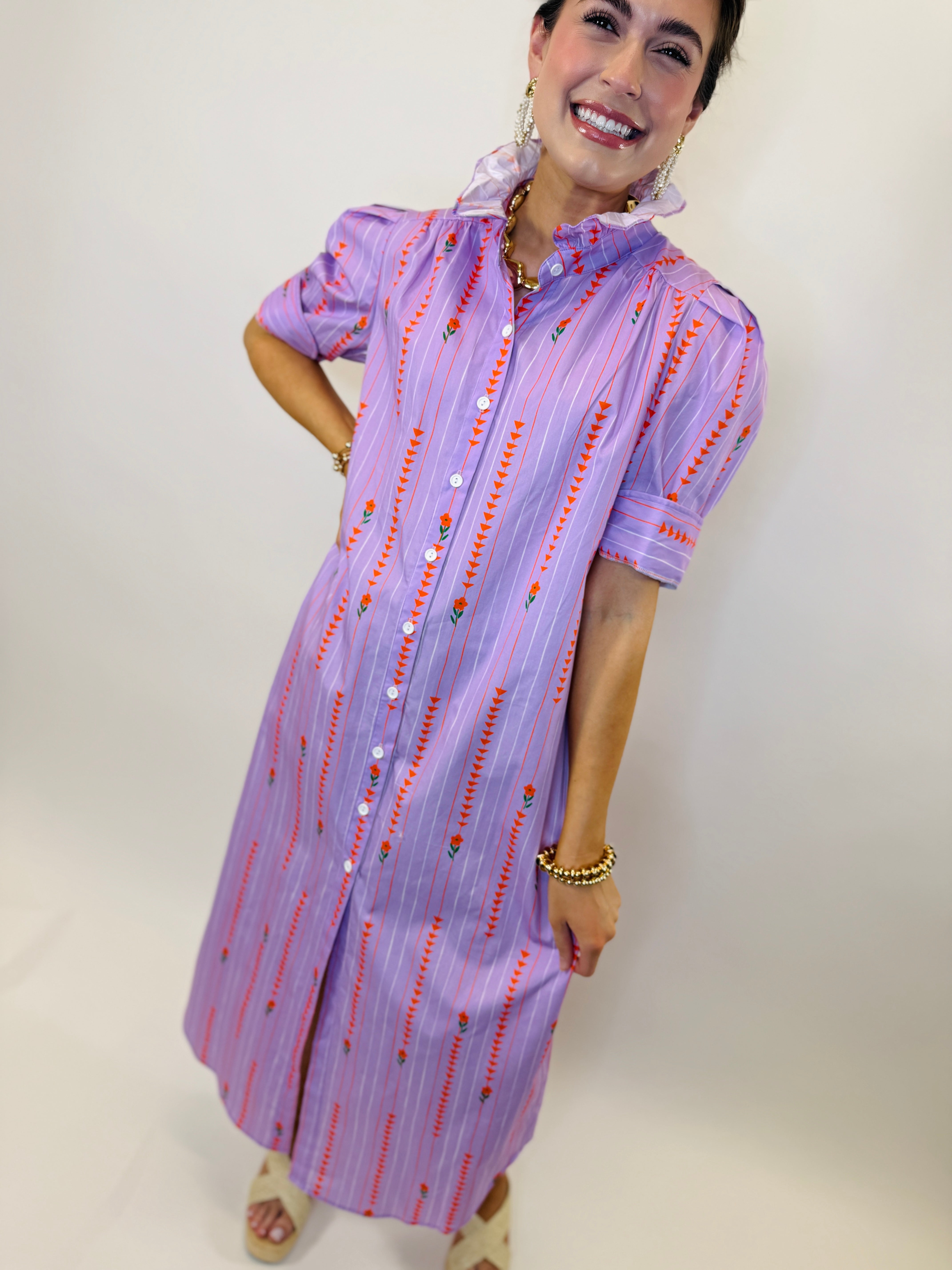 Woman wearing purple striped button-down shirt dress with red floral embroidery and ruffle collar details.