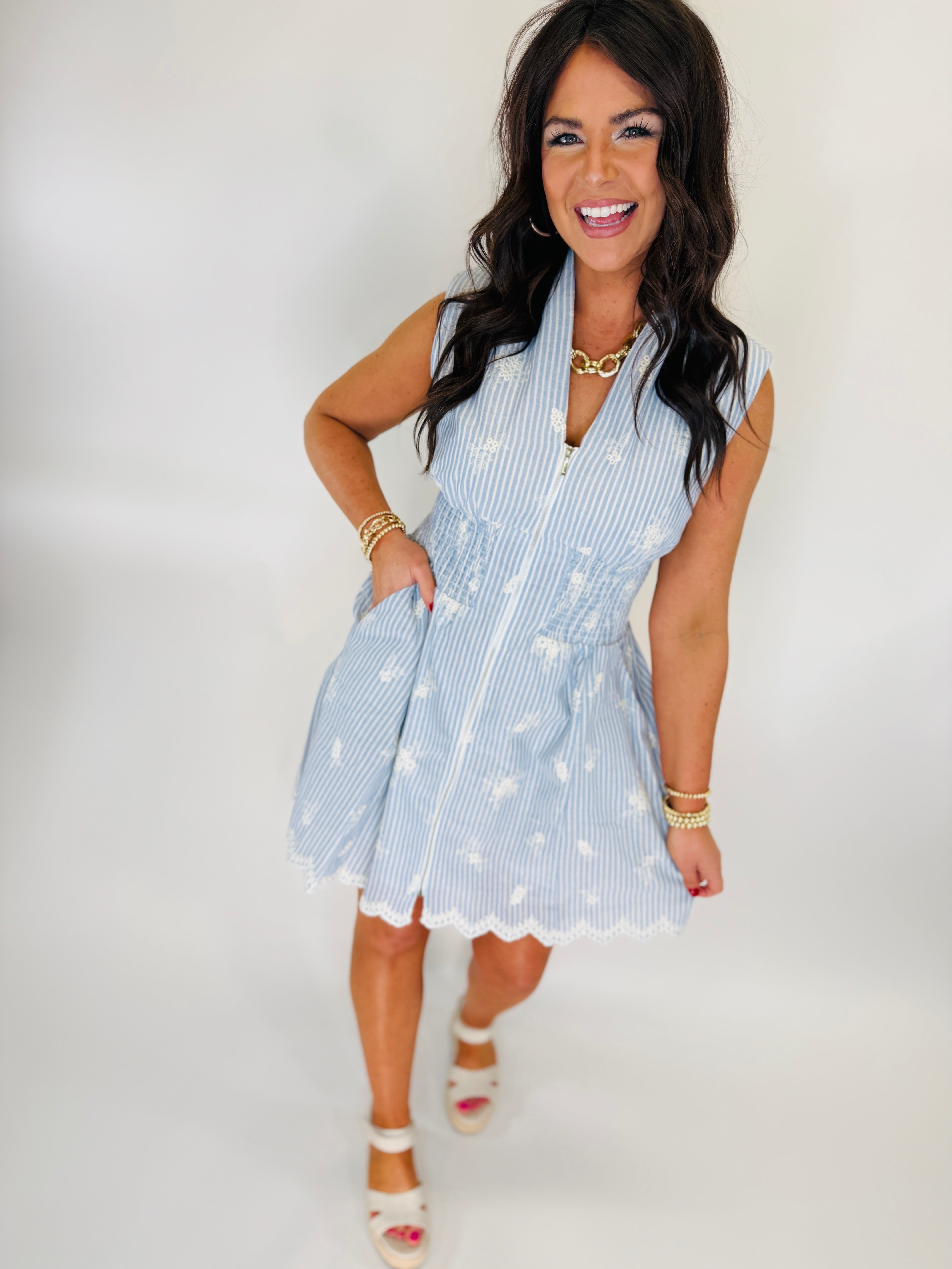 Woman wearing light blue striped sleeveless wrap dress with white floral pattern and frayed hem