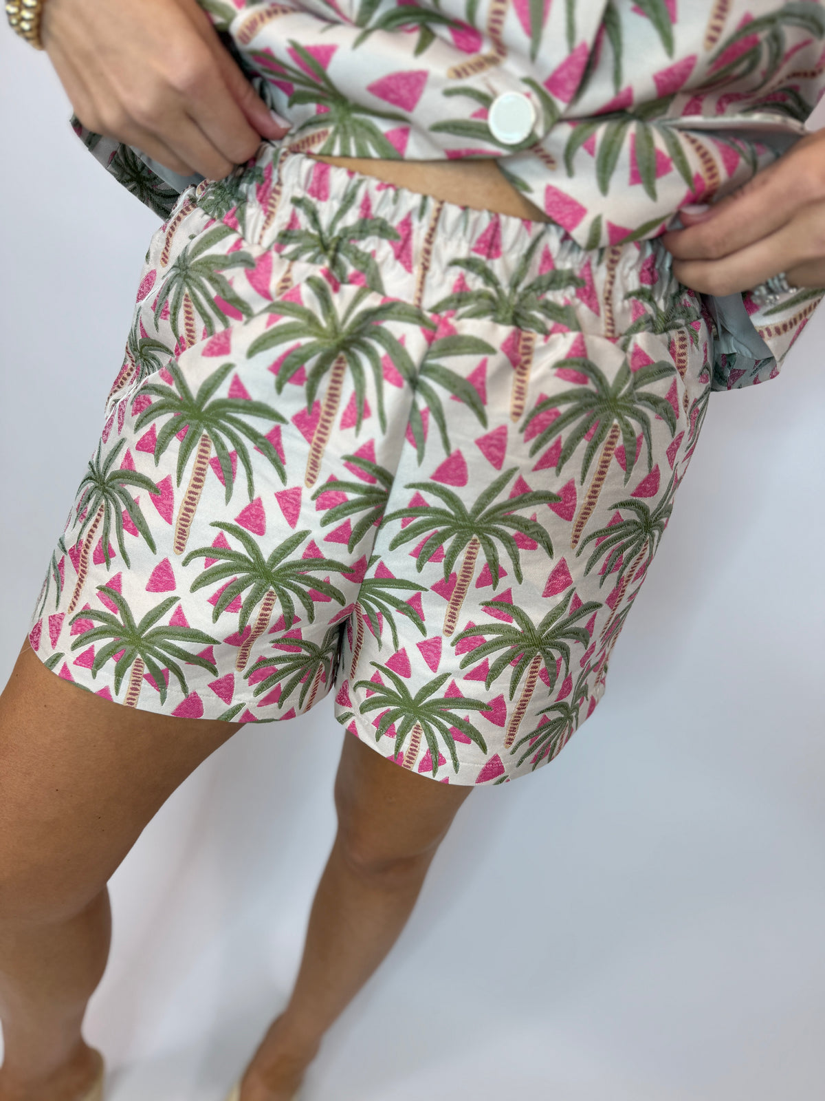 Woman wearing tropical print shorts with palm trees and pink watermelon pattern, part of Beverly Set.