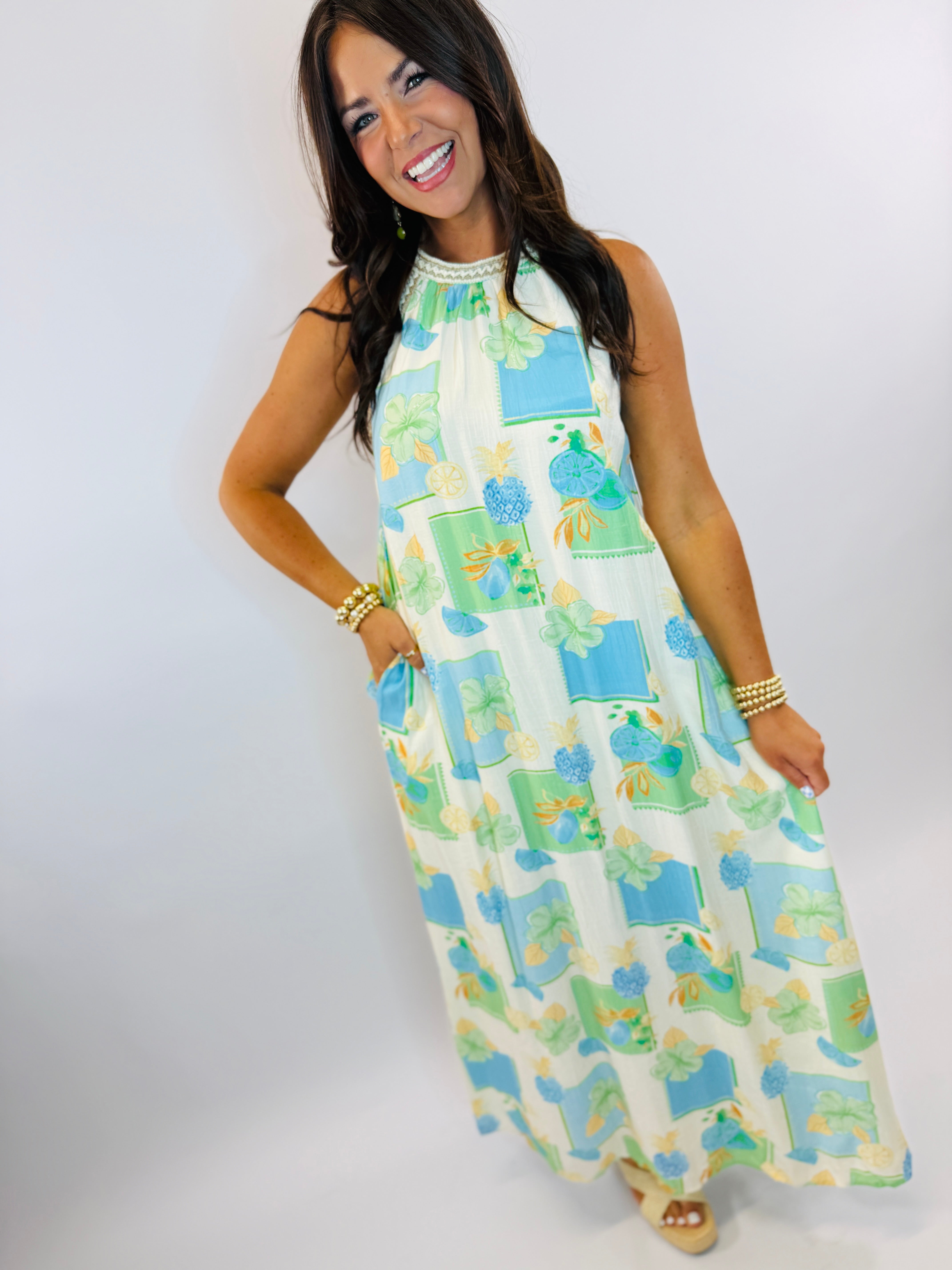 Woman wearing colorful sleeveless Bermuda maxi dress with tropical floral print in blue and green tones