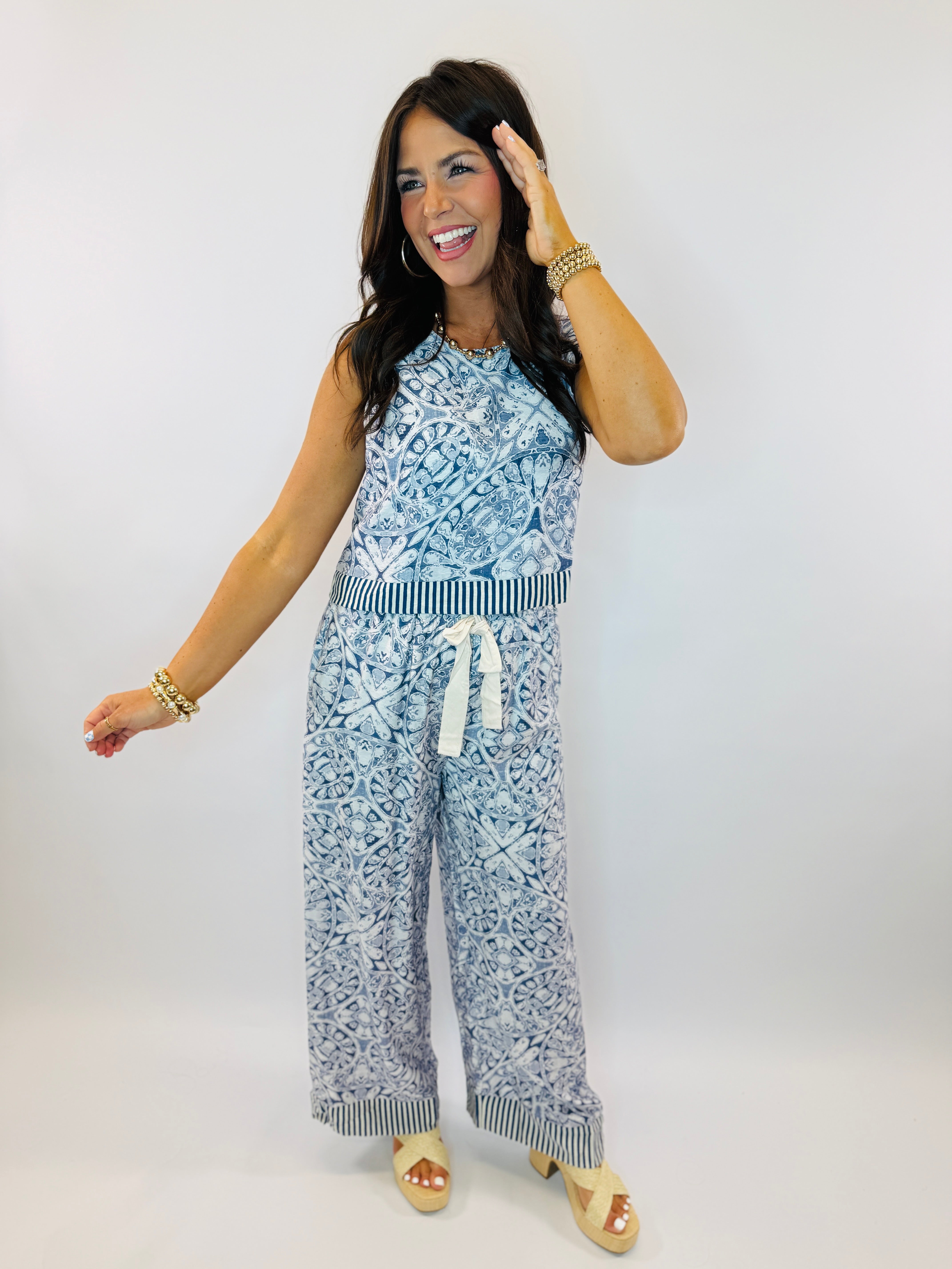 Woman wearing blue and white patterned sleeveless top and matching wide-leg pants with striped trim detailing.