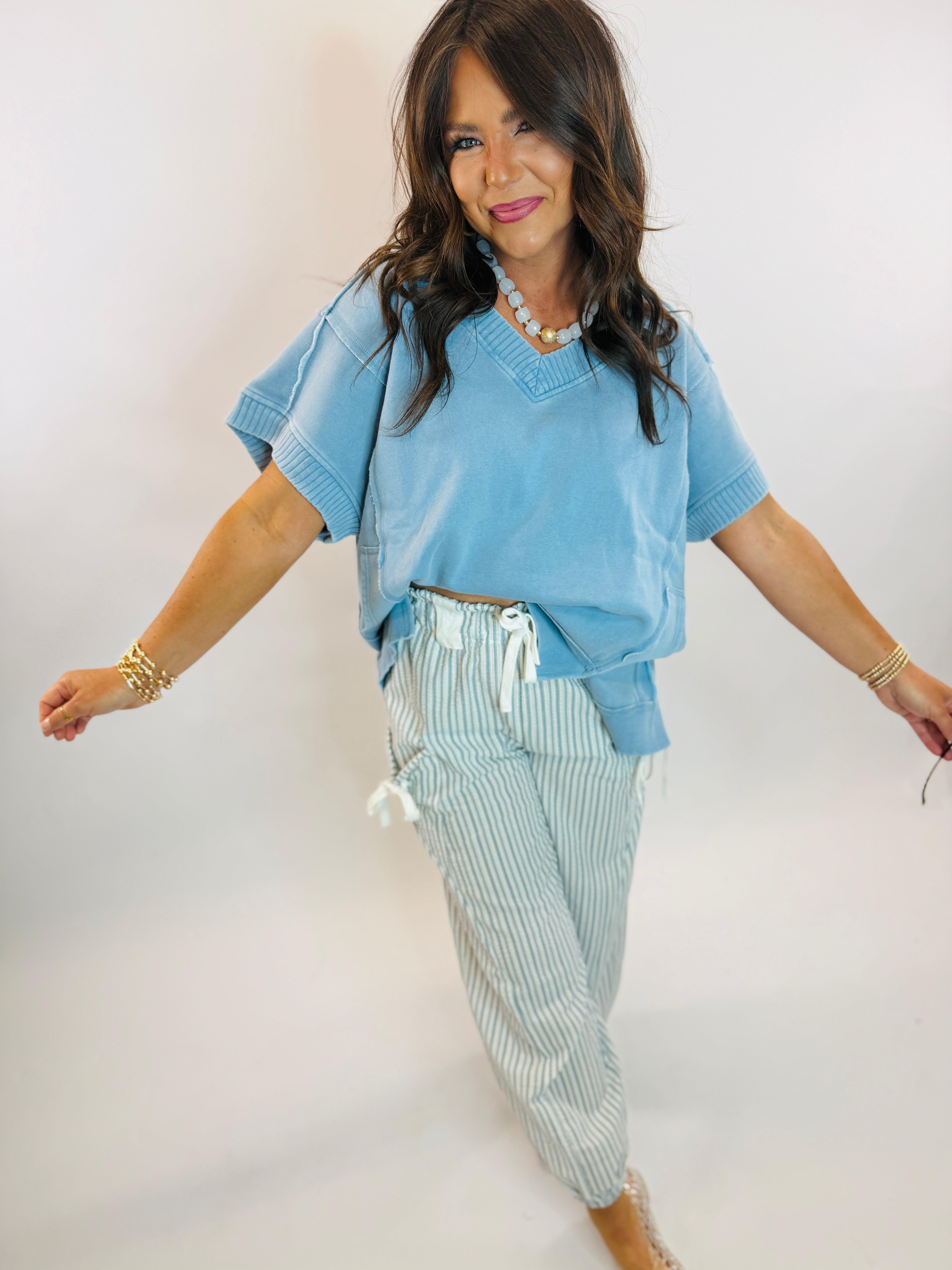 Woman wearing a light blue oversized V-neck short sleeve top with ribbed trim details.