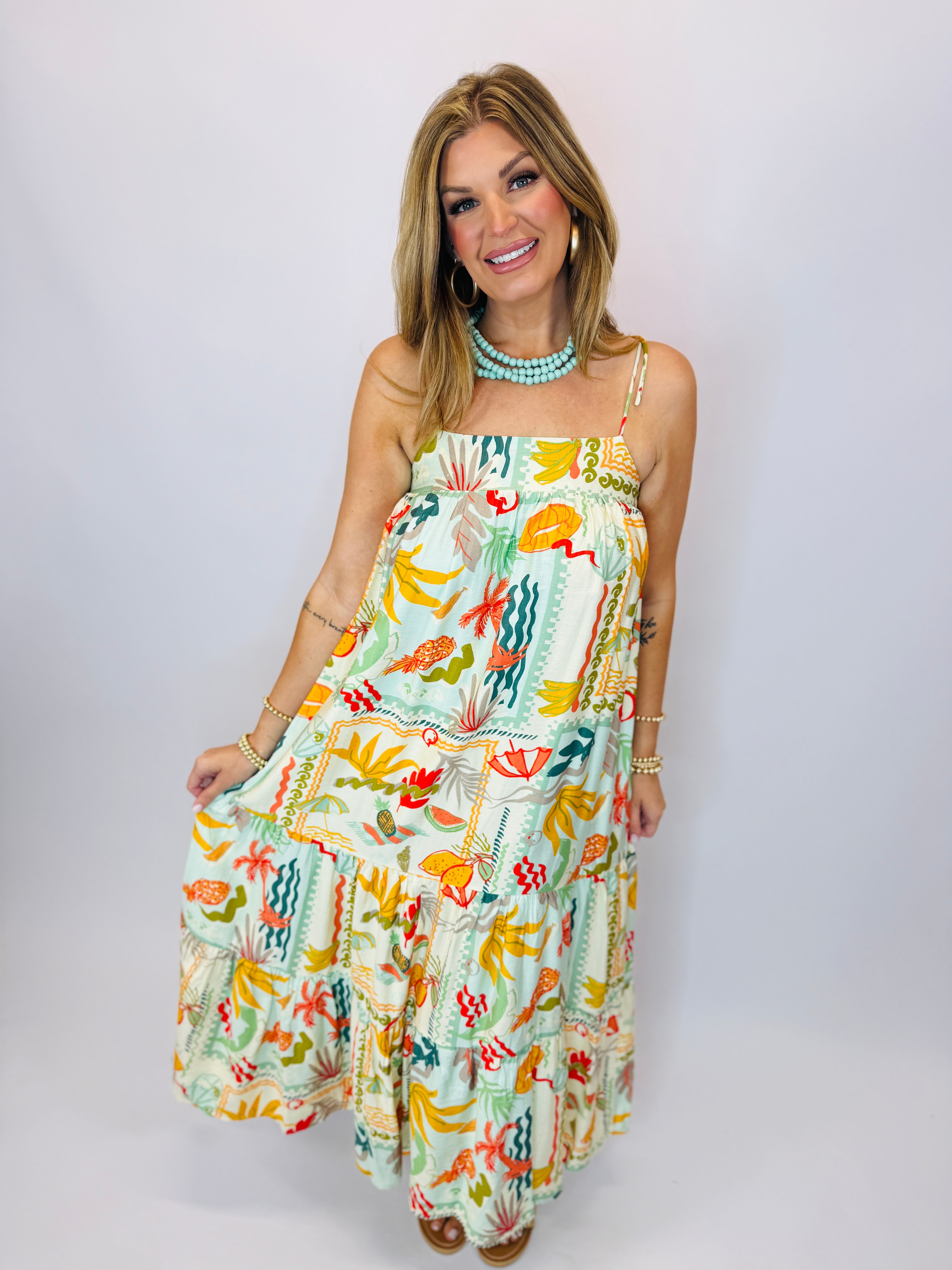 Woman wearing colorful tropical print Alani maxi dress with spaghetti straps and tiered ruffles