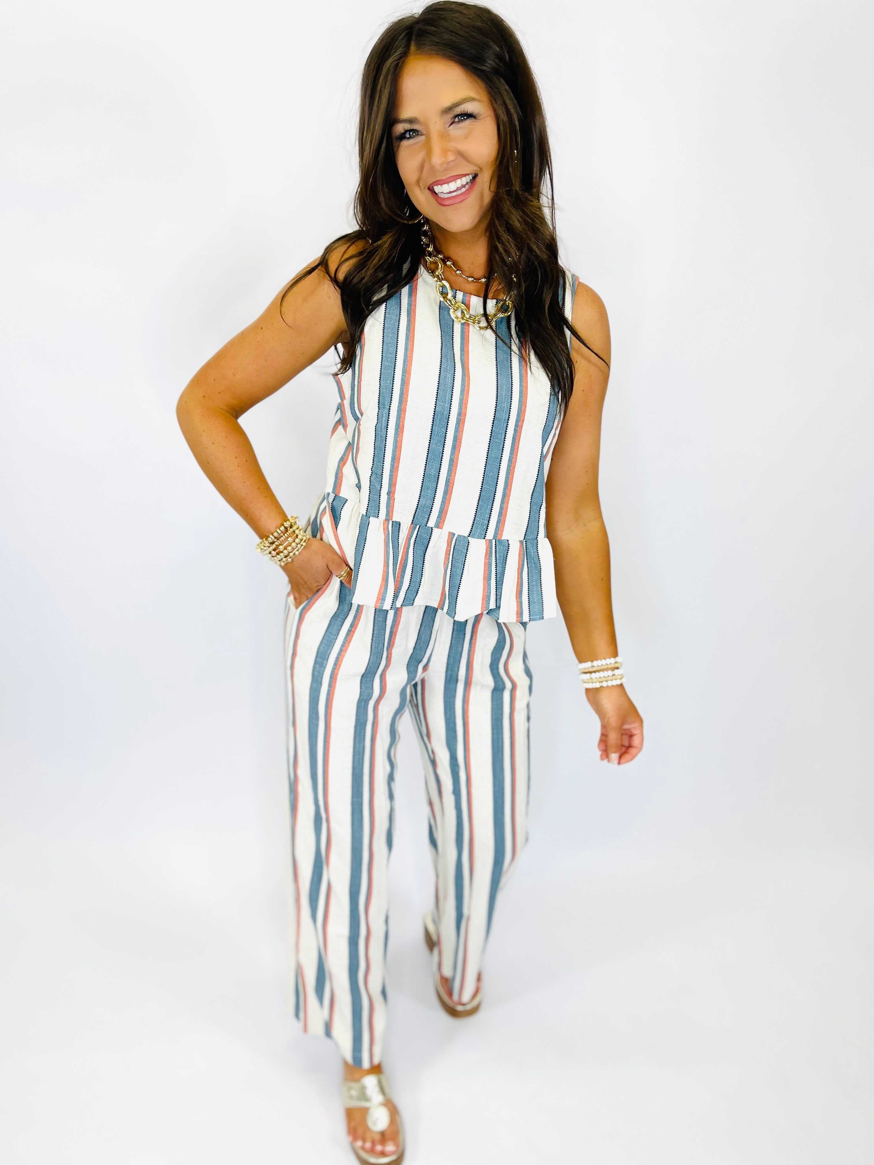 Woman wearing striped sleeveless top and matching wide-leg pants in blue, coral, and white vertical stripes.