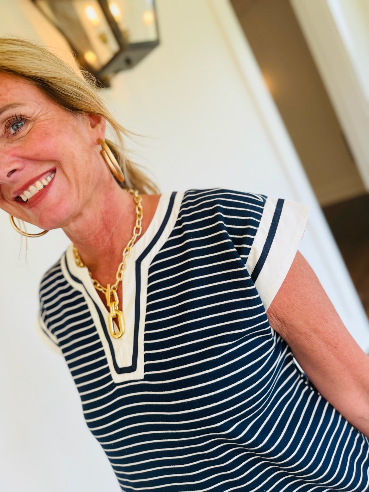 Woman wearing navy and white striped Kathy Dress with V-neckline and white trim accents.